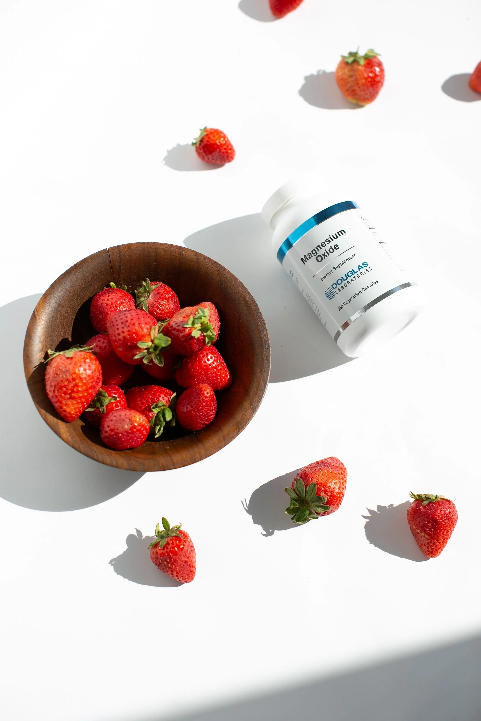 Bowl of strawberries and a bottle of magnesium vitamins