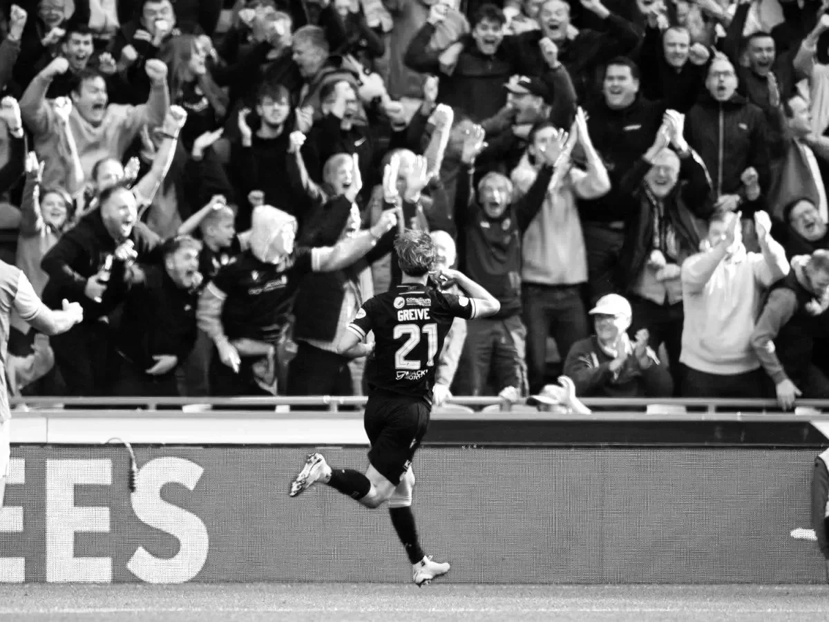 Passionate football crowd celebrating at Scottish Premiership match with players visible on pitch