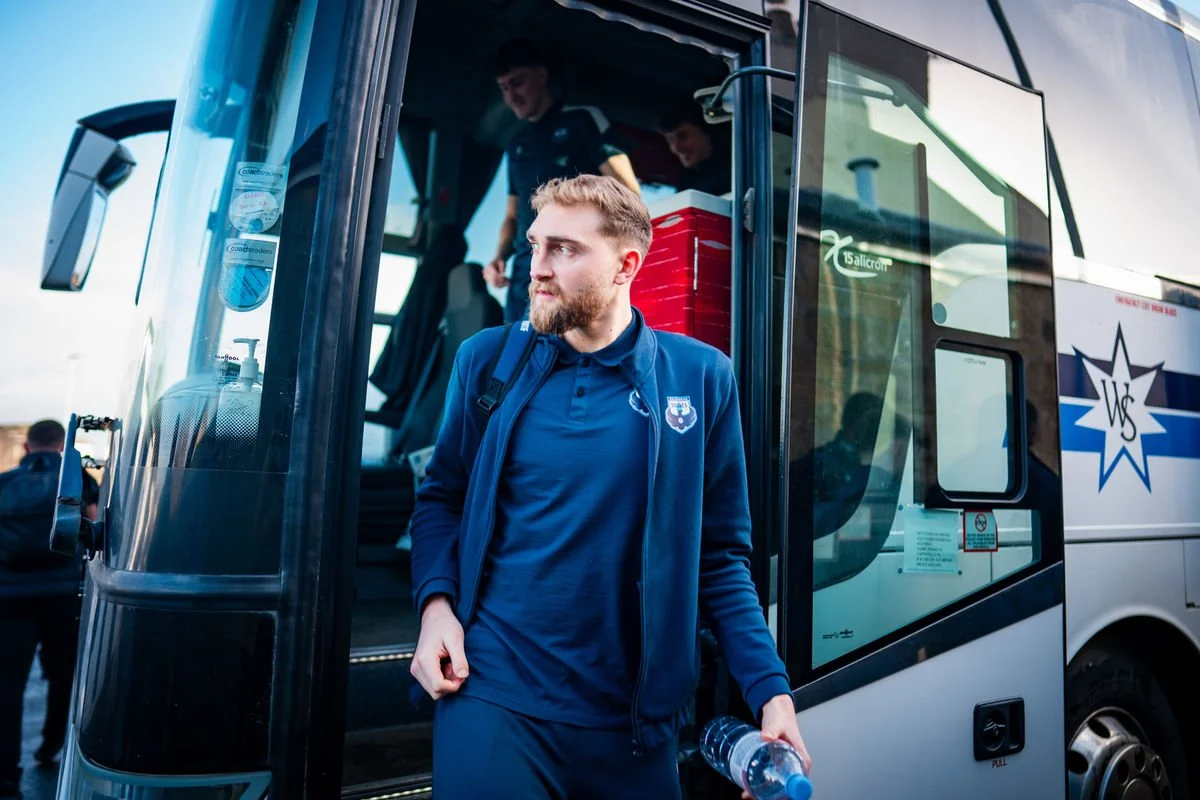 Bernie White walking through stadium tunnel in blue goalkeeper kit before a match in Scotland's Lowland League