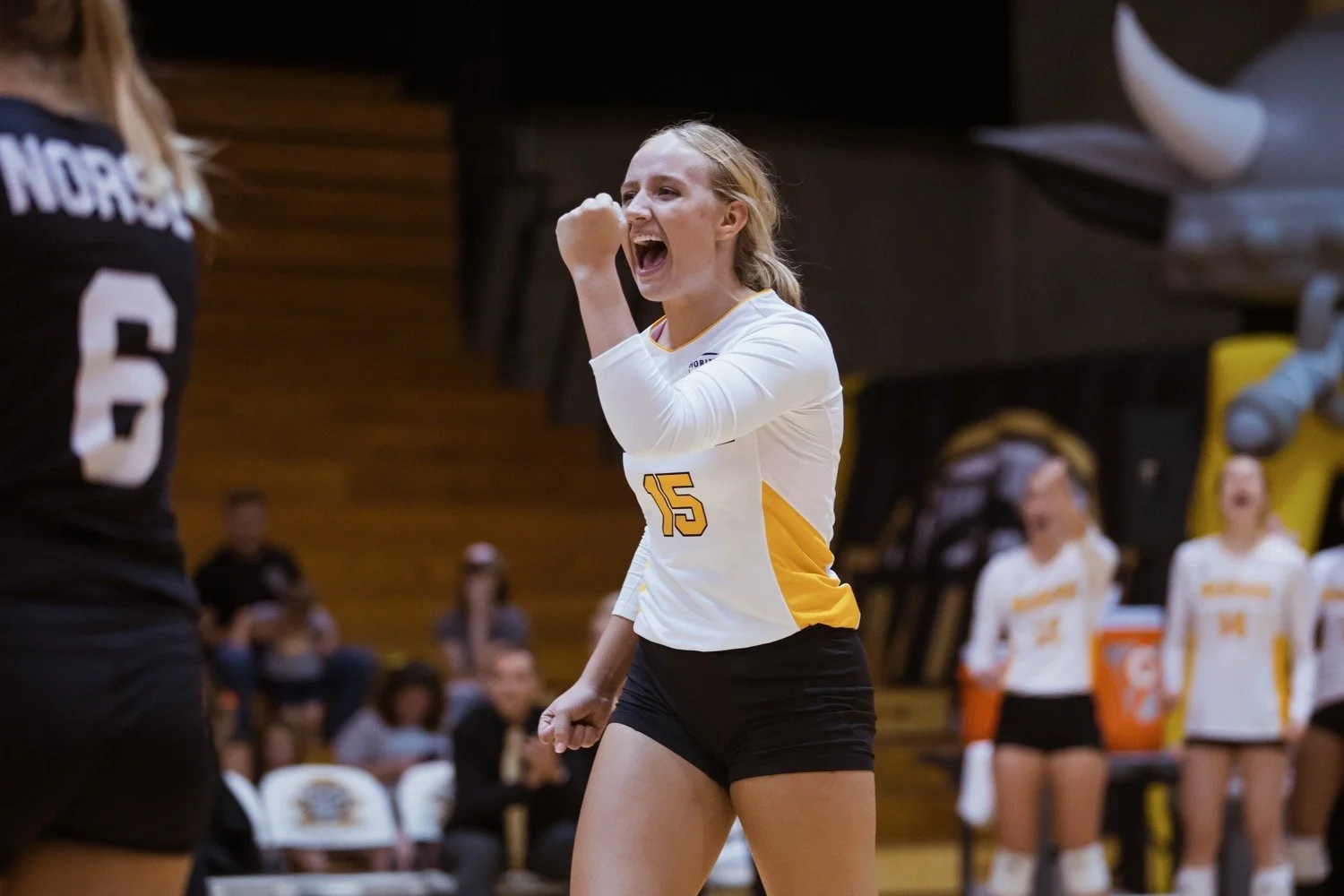 Maddy Weber celebrating point during Northern Kentucky University NCAA Division I volleyball match in white and gold uniform