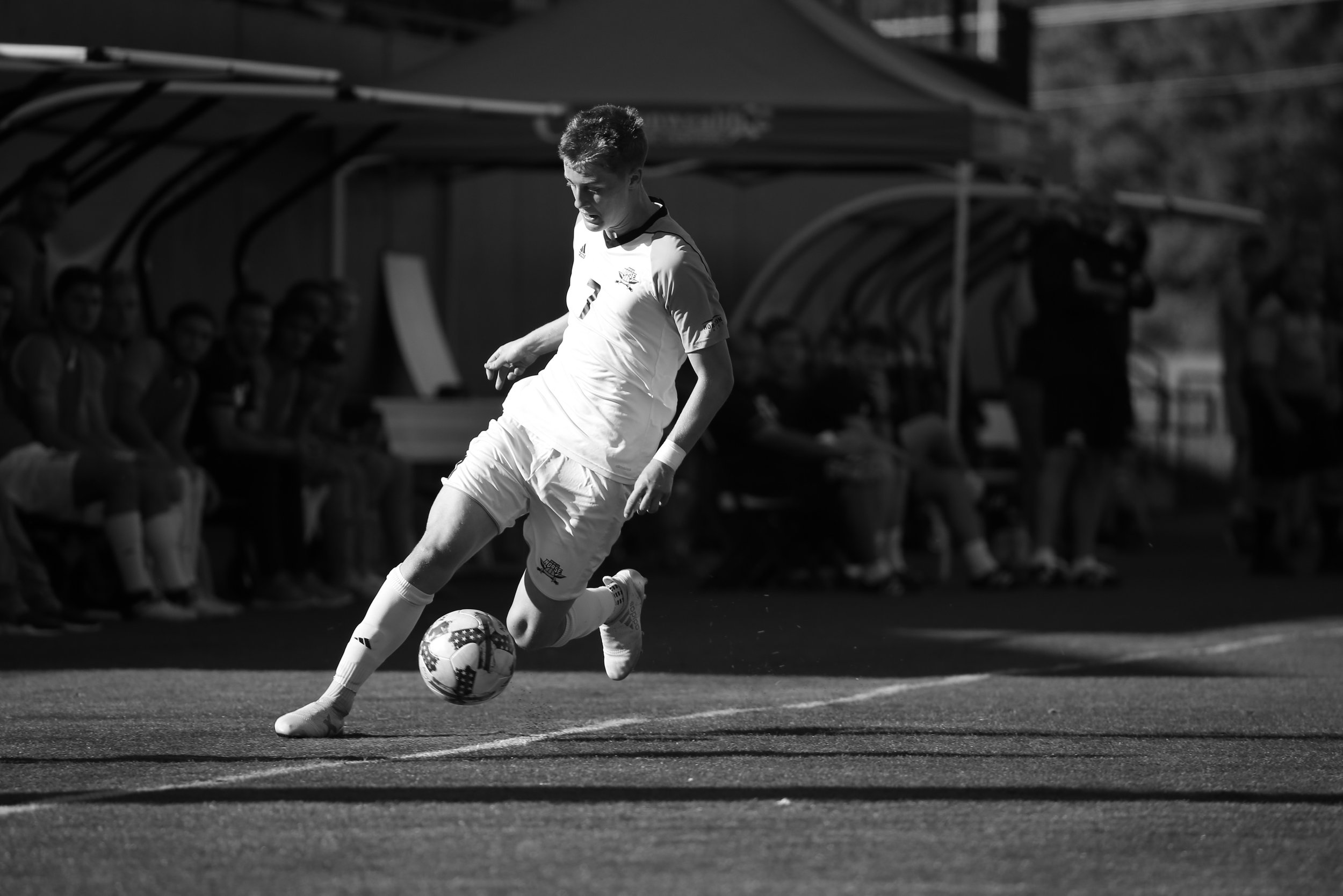 Alex Greive striking the ball during a college match for Northern Kentucky University - black and white action photo