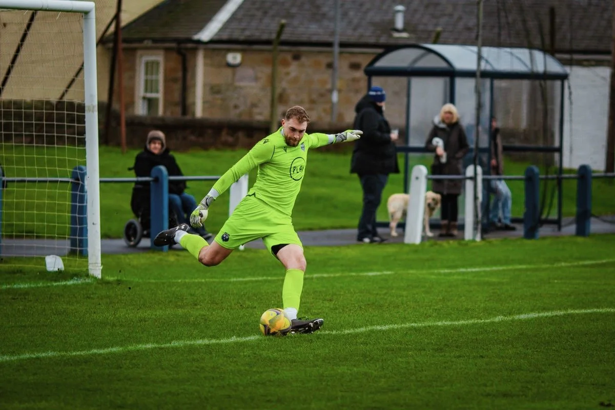Bernie White in lime green goalkeeper kit preparing to distribute the ball during training in Scotland
