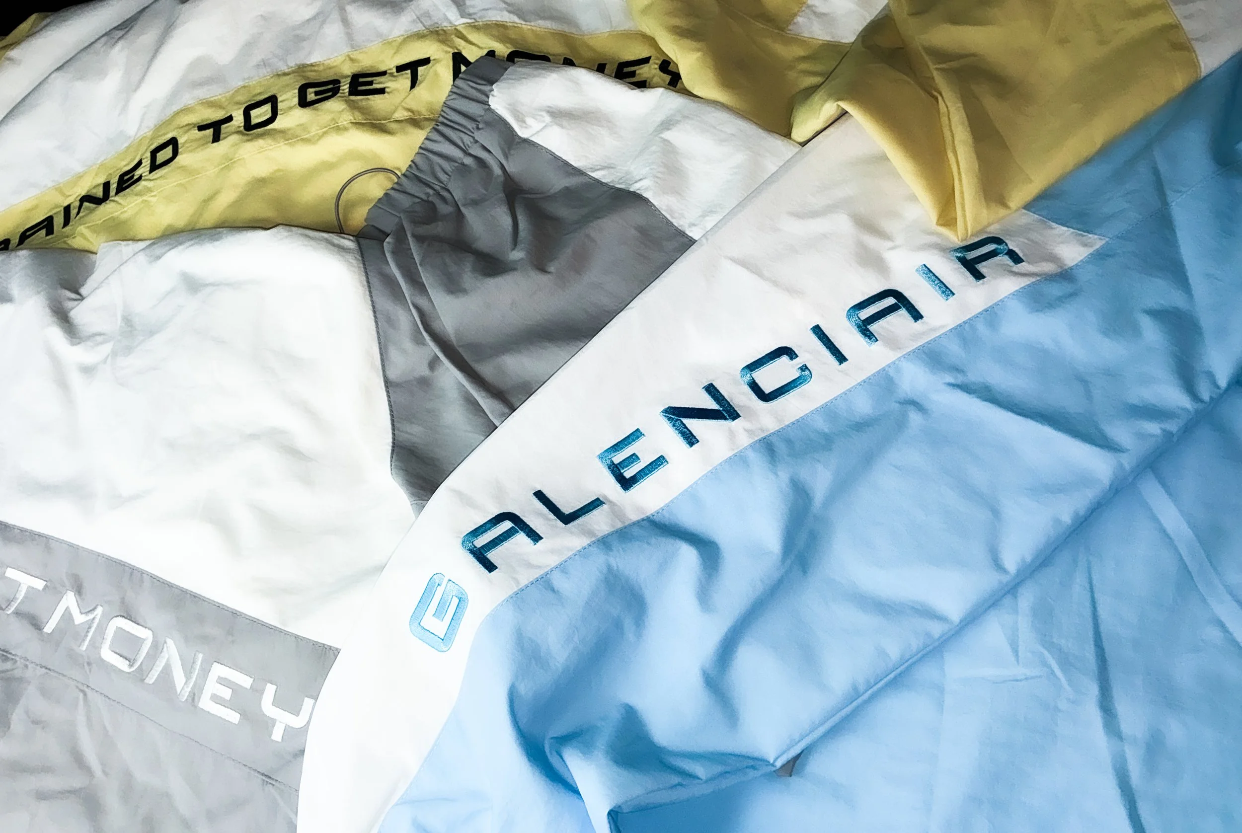 Close-up of a folded California-themed windbreaker with the word 'California' on a white section and other colored parts with text.