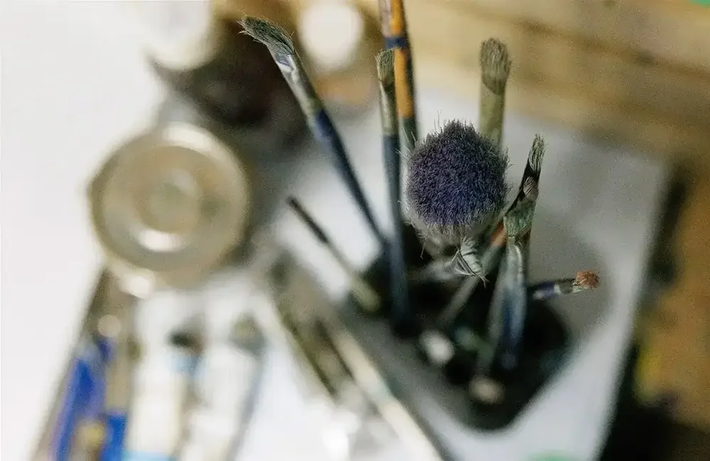 A collection of paintbrushes in a container, with various sizes and shapes of bristles visible.