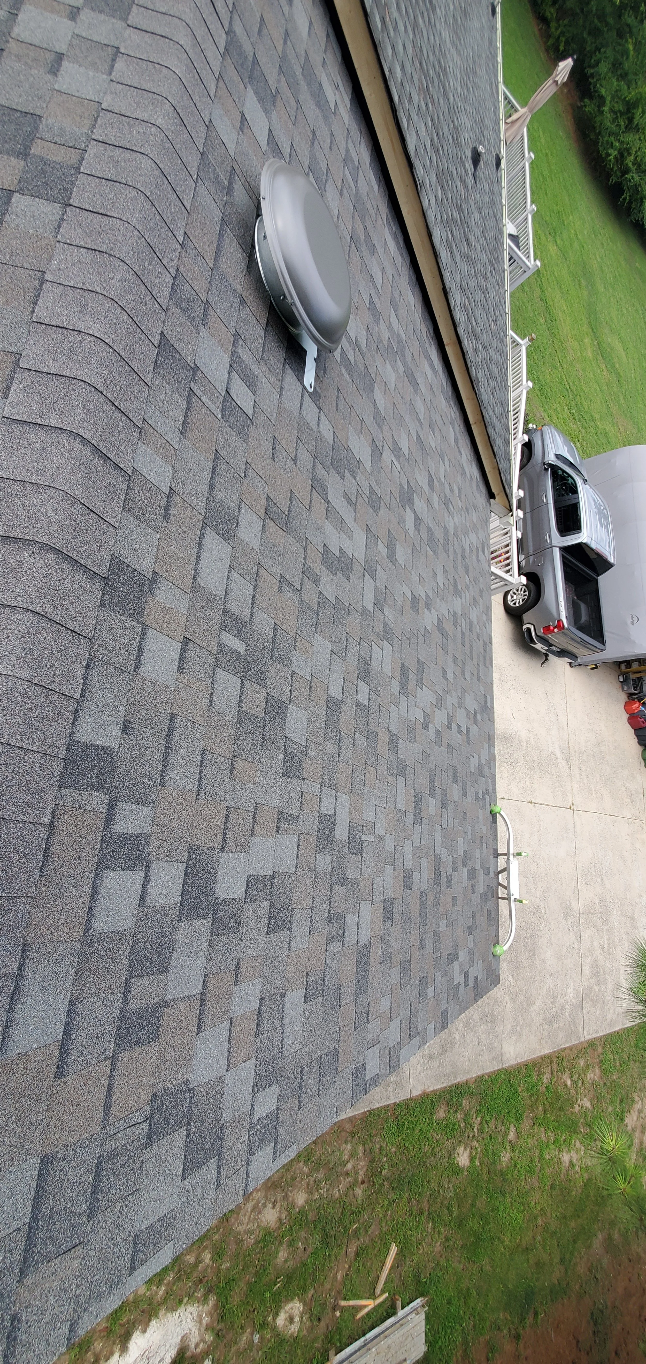 Close-up of a finished shingled roof section with a metal roof vent, viewed from above.