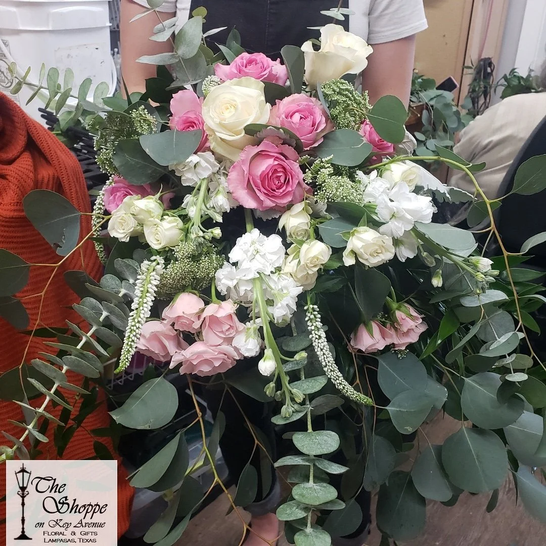 Arrangement of pink and white roses, white flowers, and green eucalyptus leaves