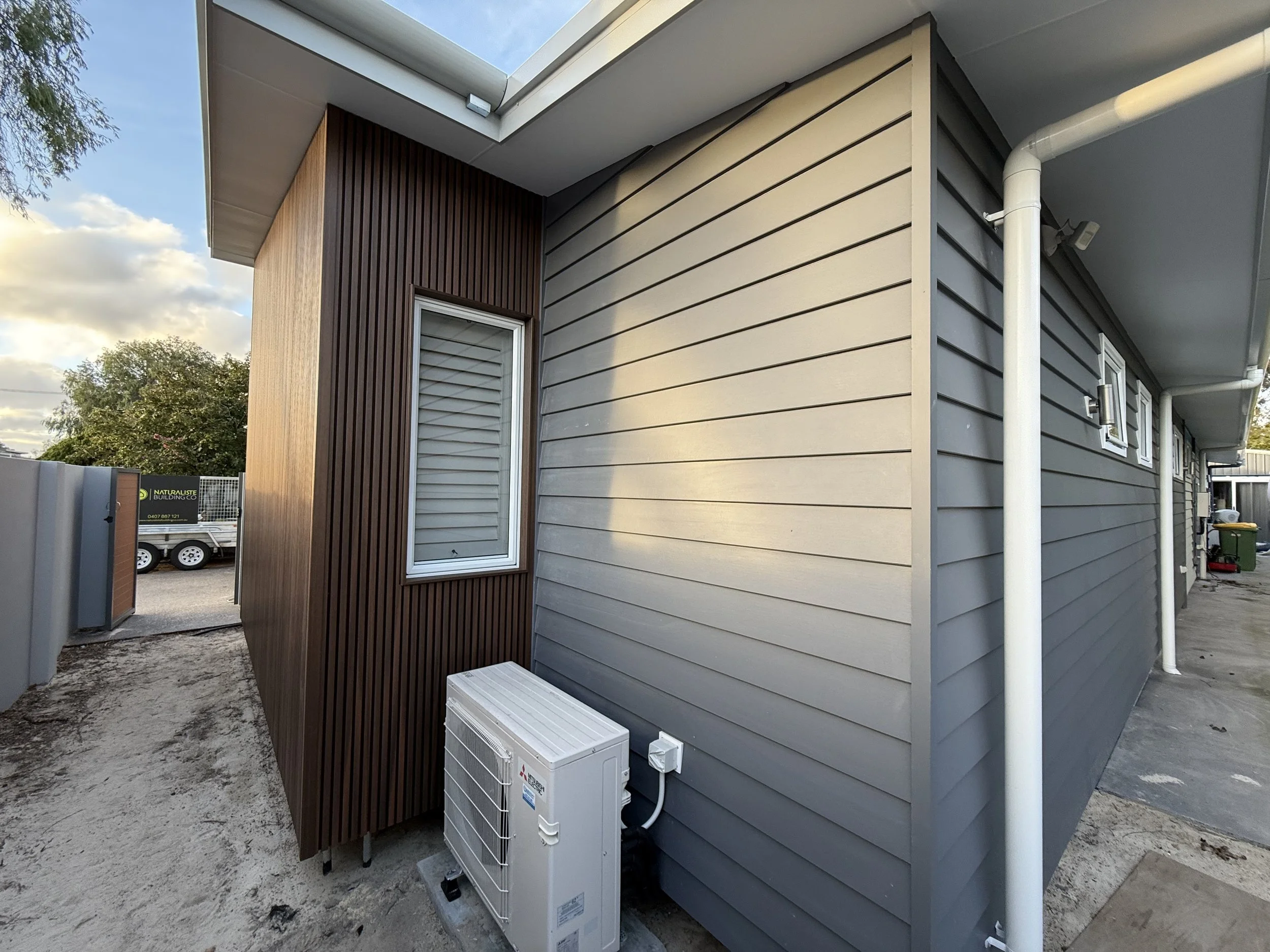 Side view of a modern house showing gray and brown exterior siding, built by local vasse builder