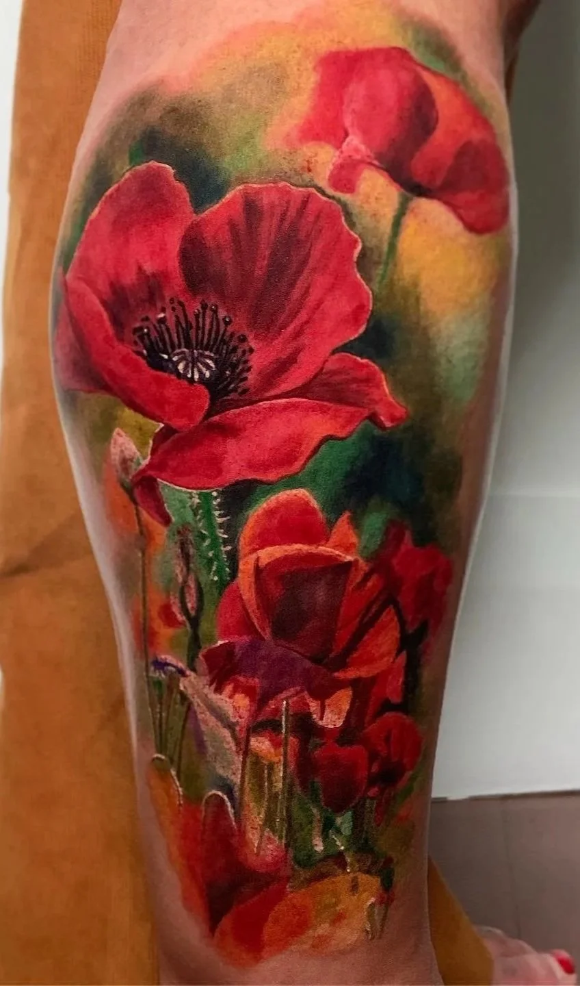 Colorful tattoo of red poppy flowers on a person's arm.