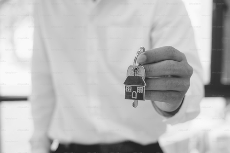 Person holding a keychain with a house-shaped keyring.
