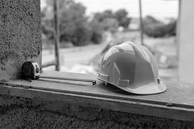 A white construction helmet and a tape measure on a windowsill.
