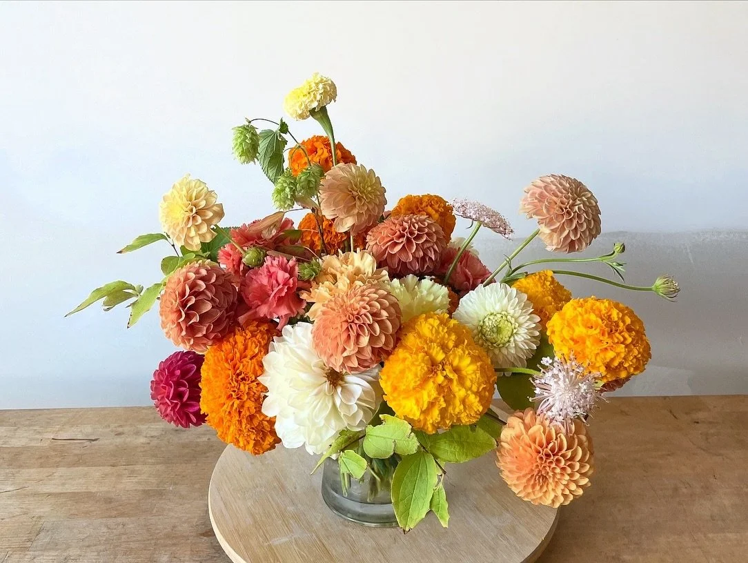 Fluffy layers of fall dahlias, marigolds and hops for an autumn wedding reception. Pops of orange are joyful and bold, and my favorite this time of year. Flower forward arrangements made this mountain ceremony &amp; celebration so glamorous.