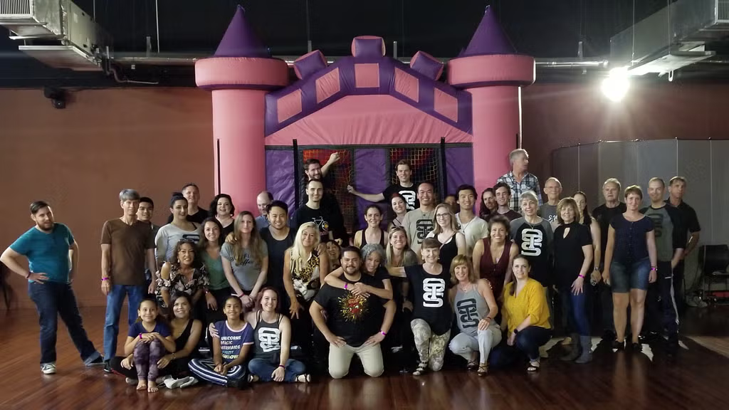 Group picture in front of a pink castle bounce house at the first Meltdown