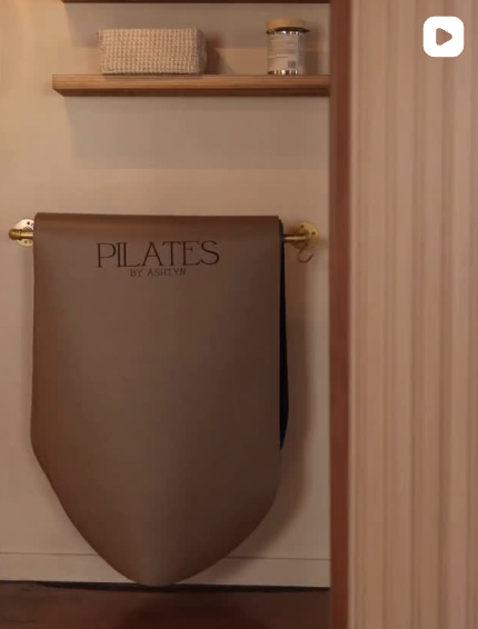 Pilates branded wall mounted equipment holder displayed in a neutral toned studio interior