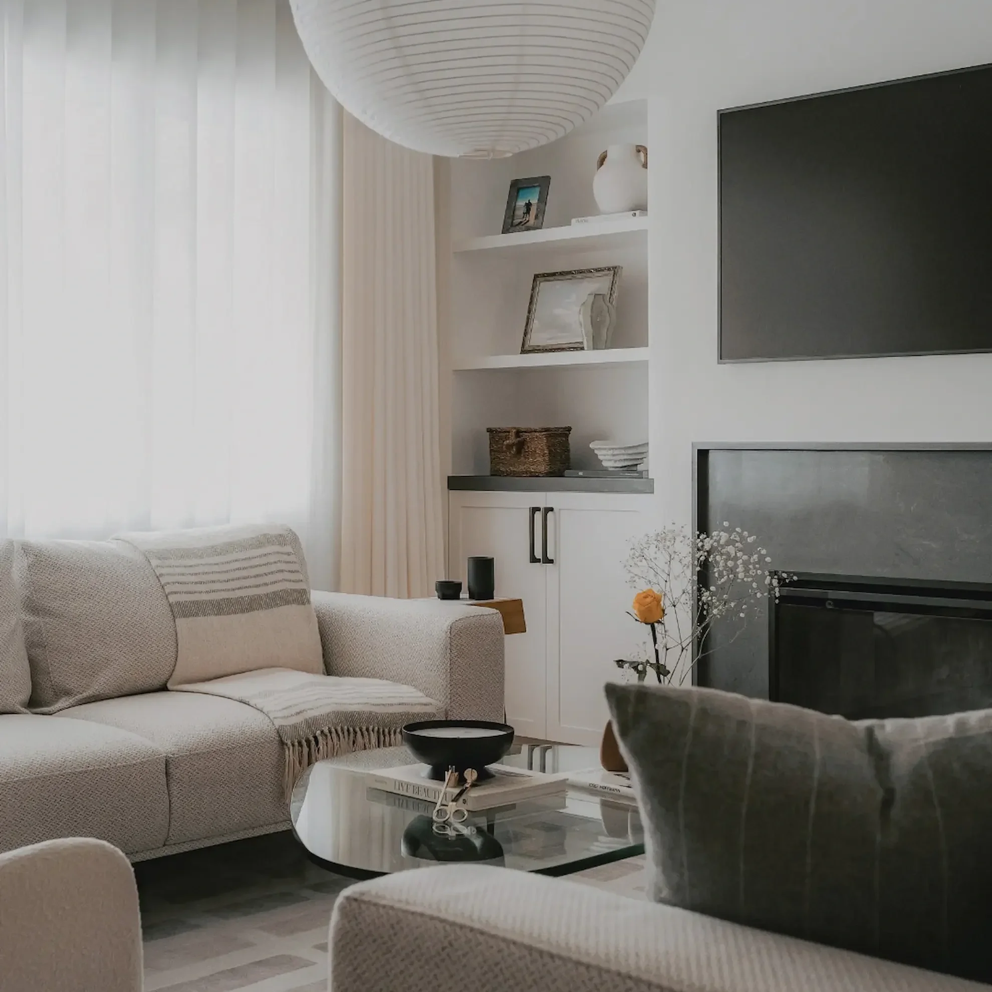 Organic modern living room in Toronto with a large paper lantern pendant light, neutral textured sofa, and custom built-in shelving by Claire Design Studio.