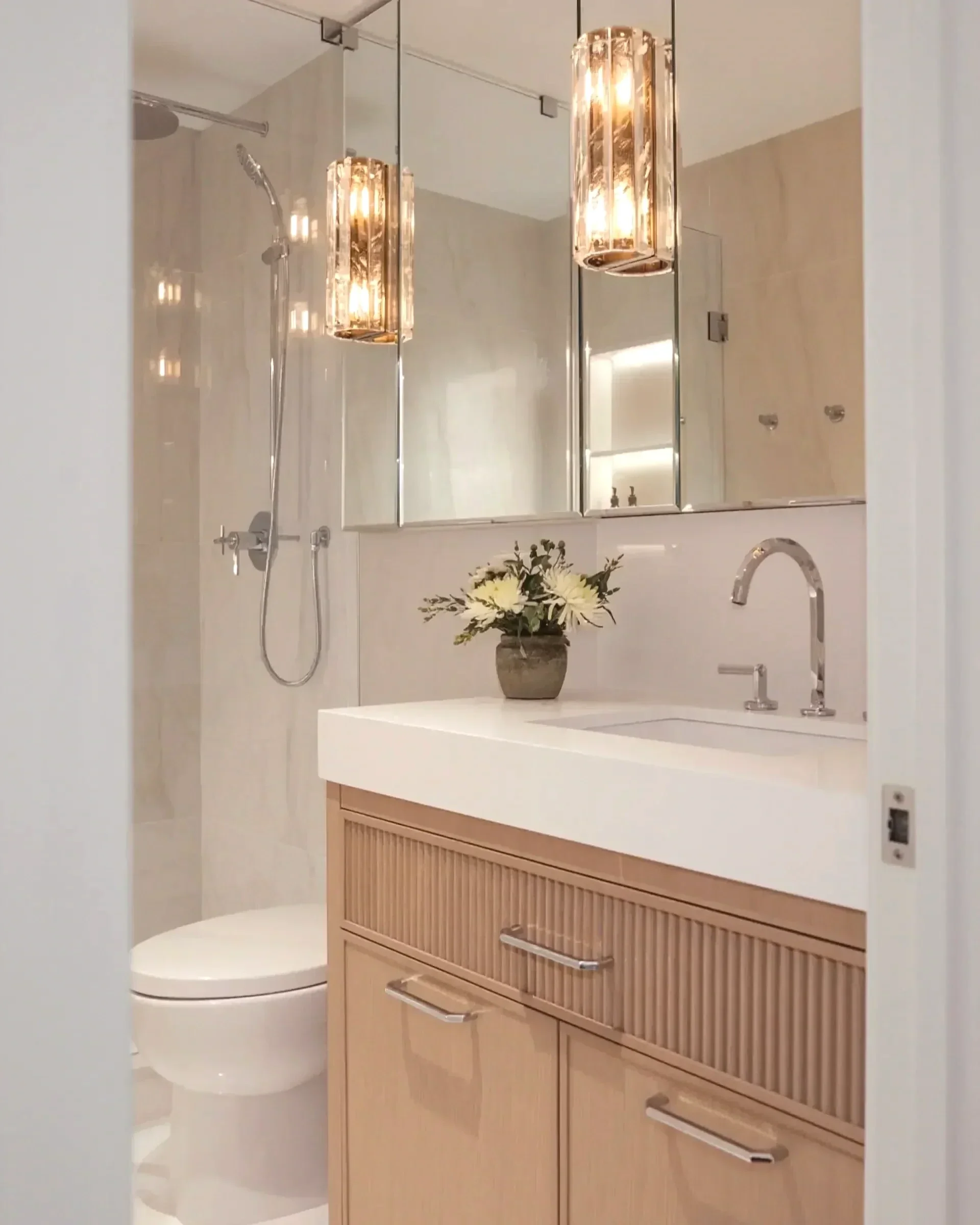 Luxury bathroom in Toronto with a fluted wood vanity, white stone countertop, and elegant glass sconces by Claire Design Studio.
