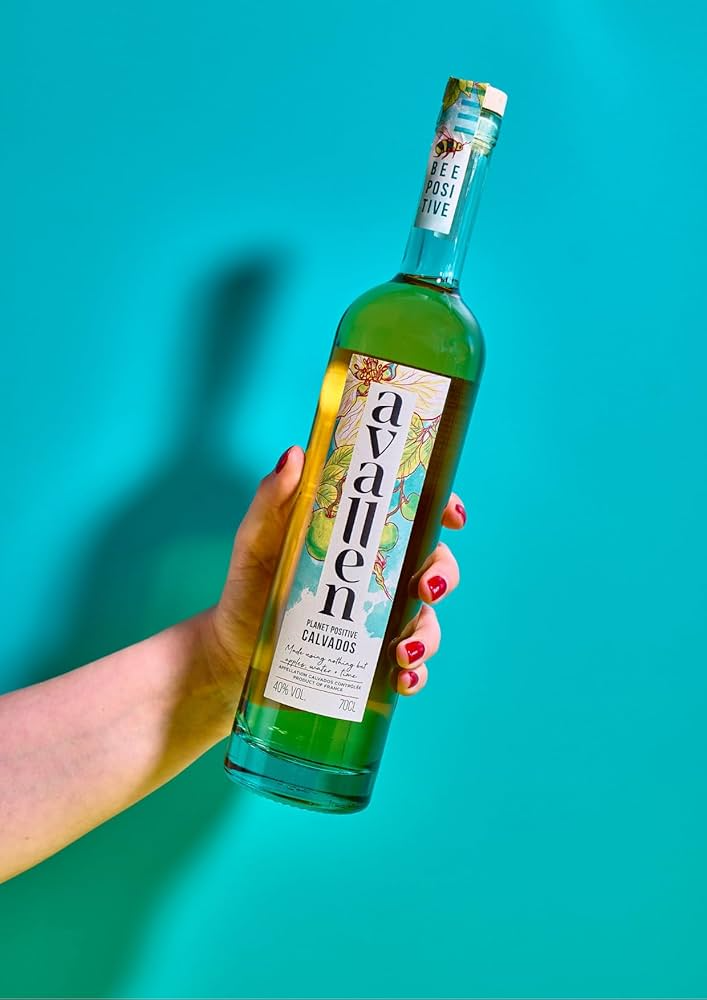 Avallen Calvados bottle held against vibrant blue background – a sustainable apple brandy promoted by Noble Spirits.