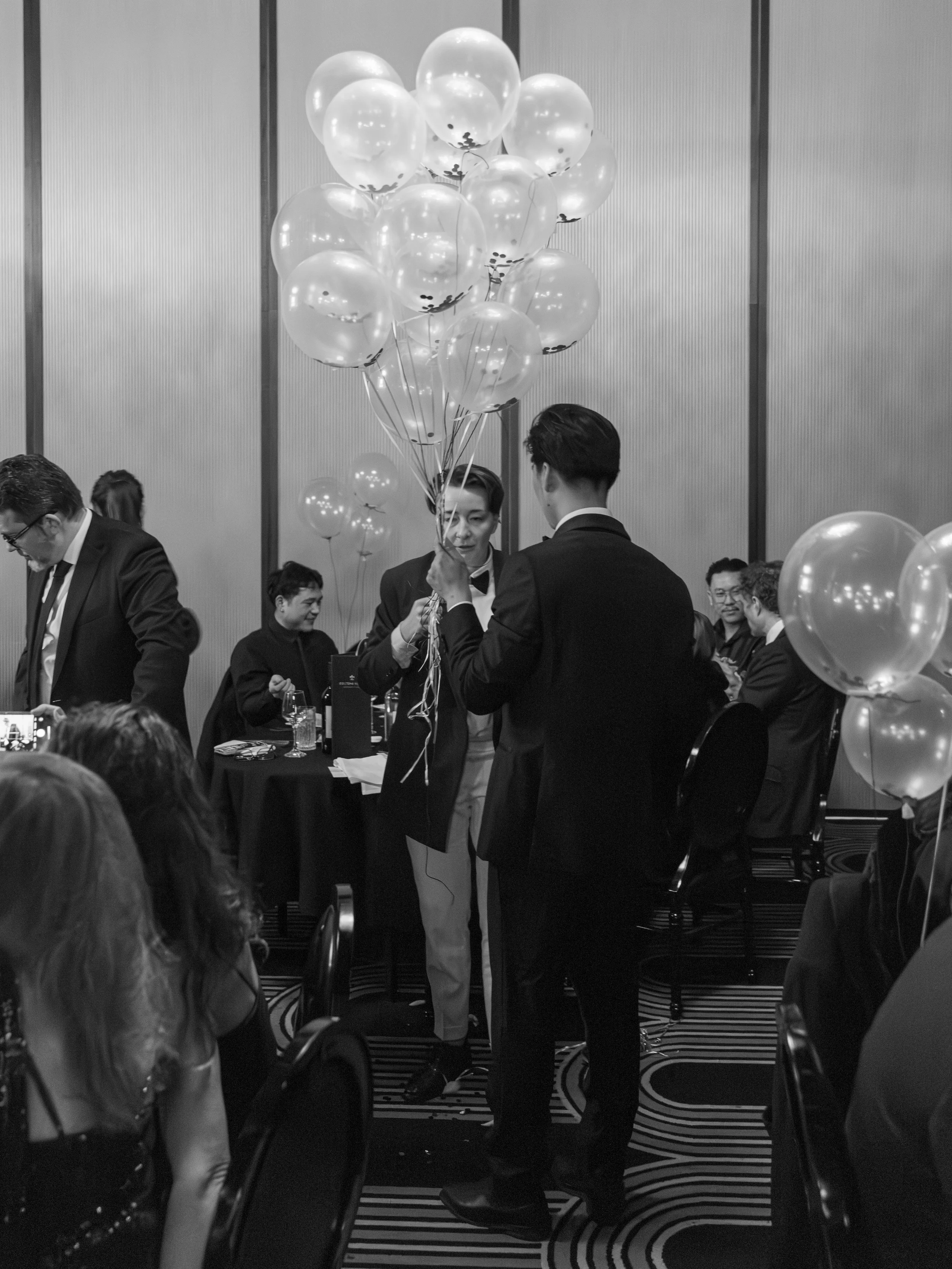 Guests holding raffle balloons at gala dinner.