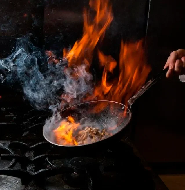 Live-fire cooking technique in action at Magma’s open kitchen, emphasising the restaurant’s flame-driven culinary style.