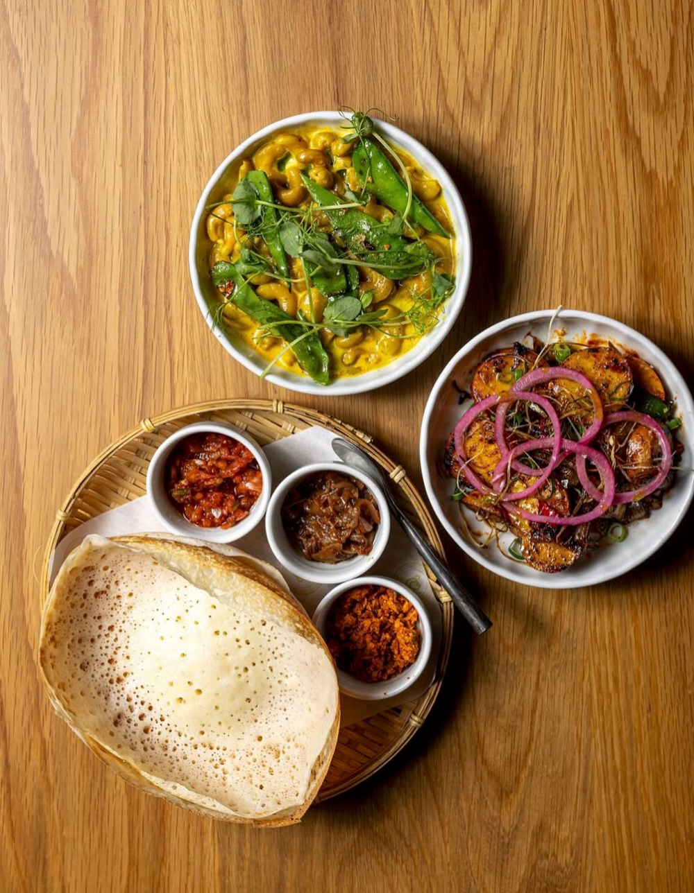 Sri Lankan hopper served with sambals, eggplant, and vegetable curries on a wooden table at Kurumba Surry Hills