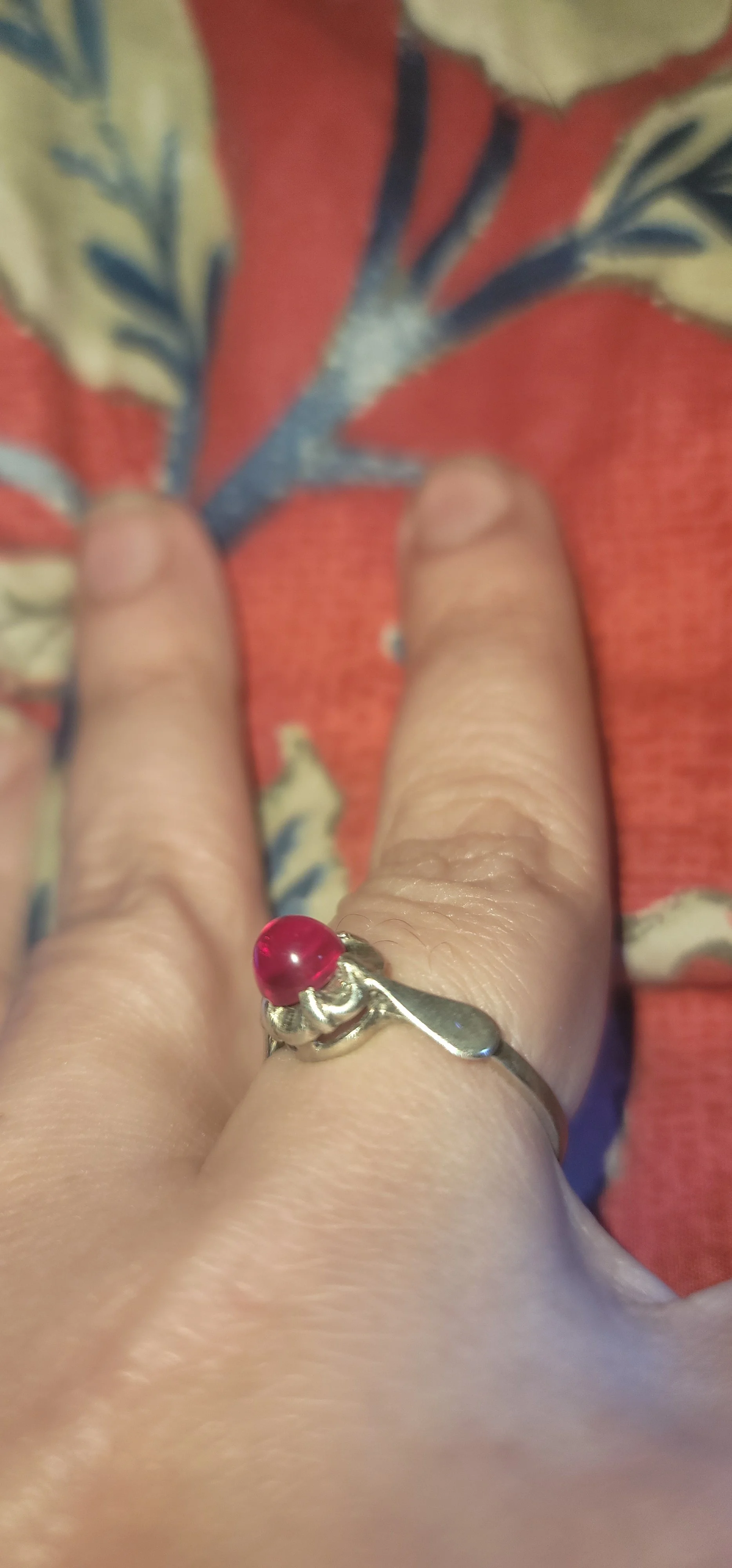 The same flame-fusion ruby ring worn on a finger in ordinary light