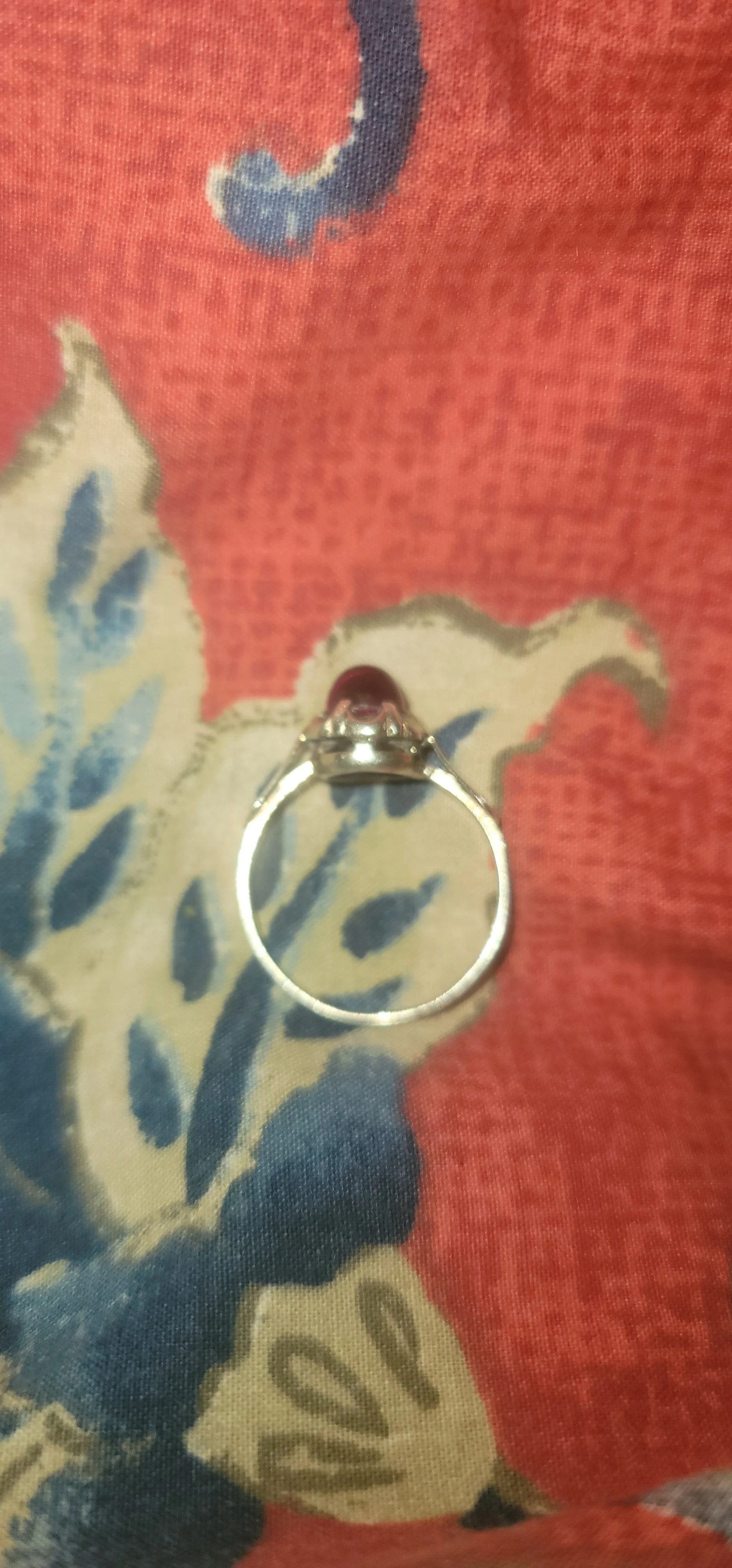 Top view of the flame-fusion ruby ring, a single smooth dark-red cabochon in a silver band
