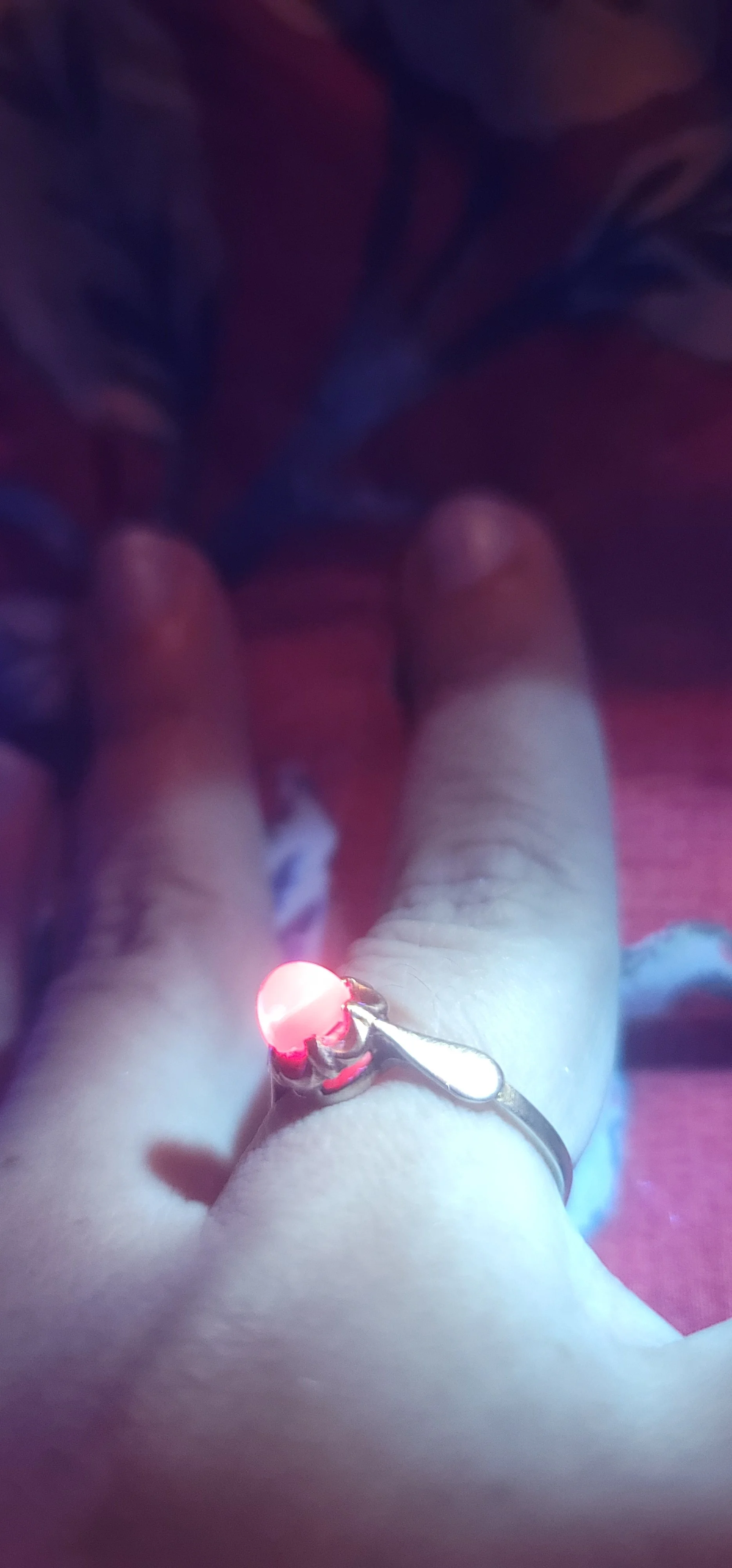 Soviet flame-fusion ruby ring held up to the light, its red cabochon glowing