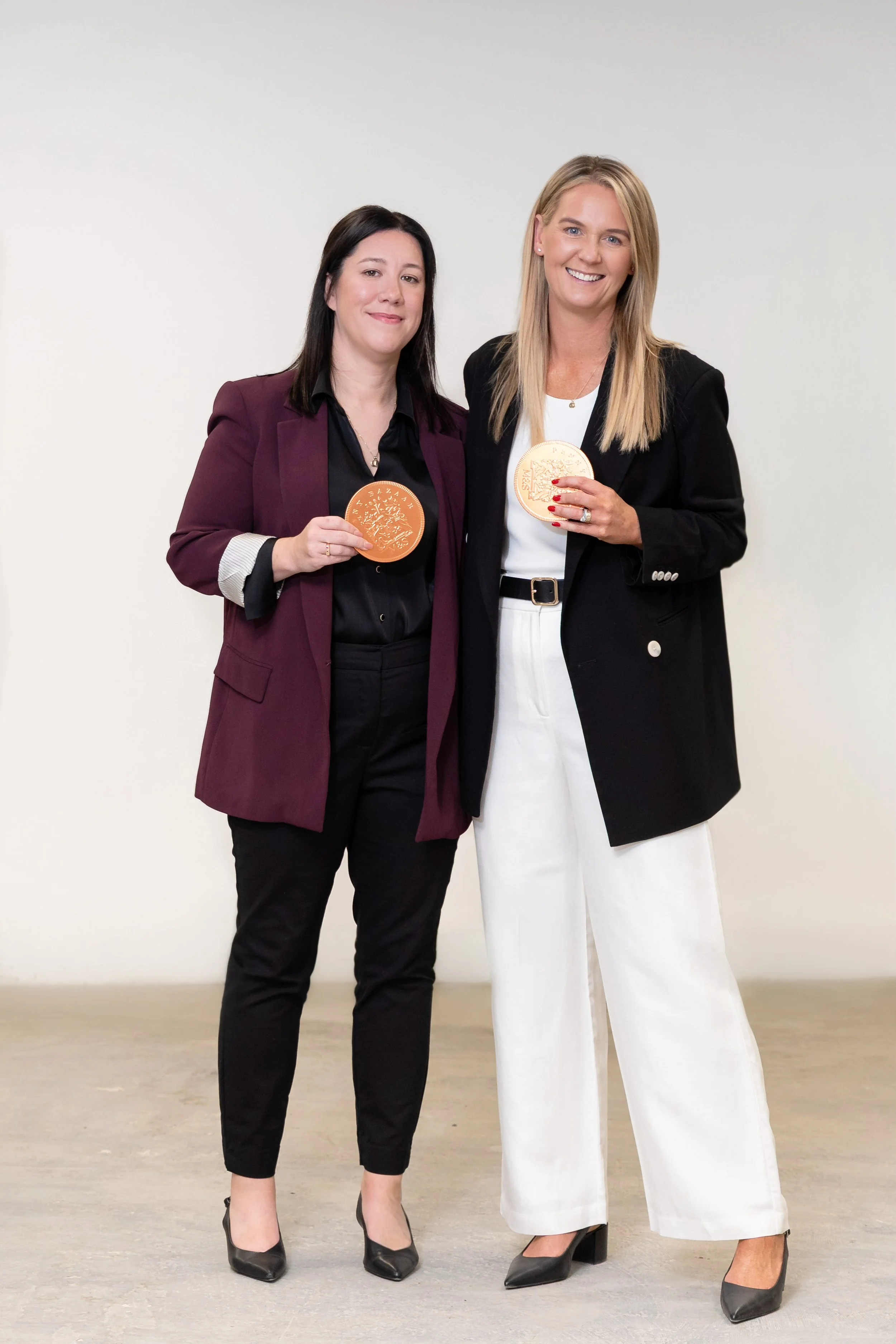 Two women standing together with gold pennies