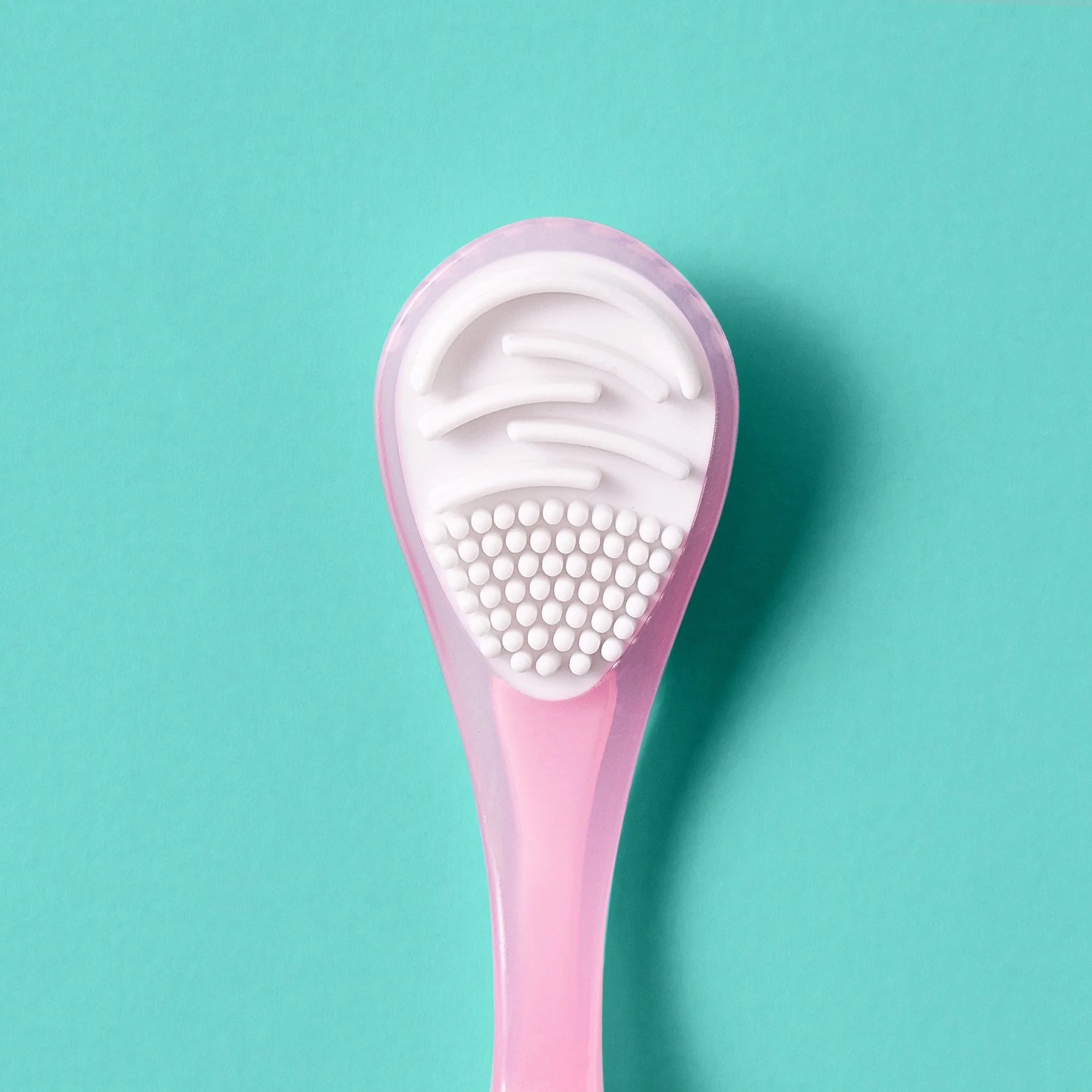 A pink and white foot spa massage brush with a textured surface, isolated on a teal background.