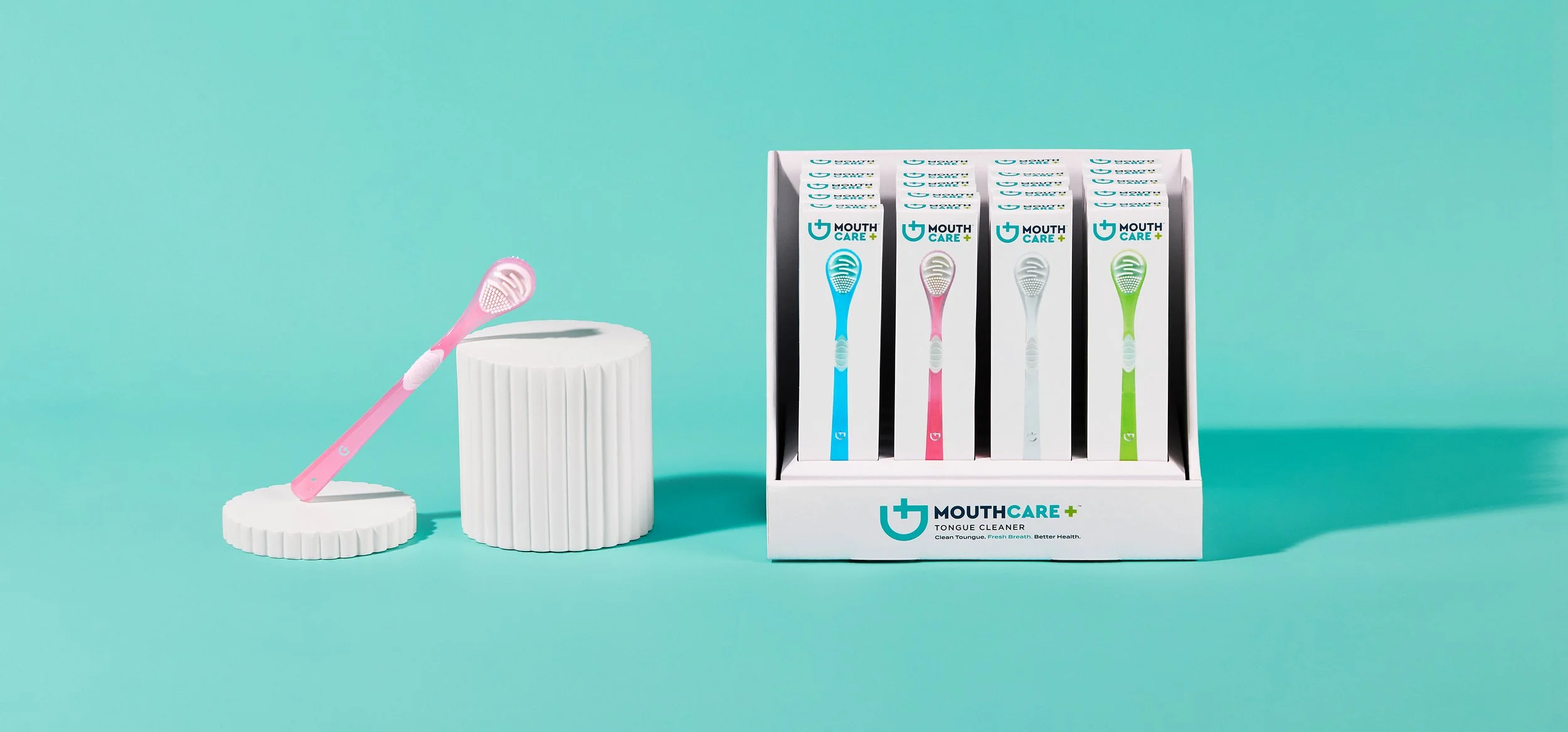 Display of colorful toothbrushes and mouth care product packaging on a teal background.