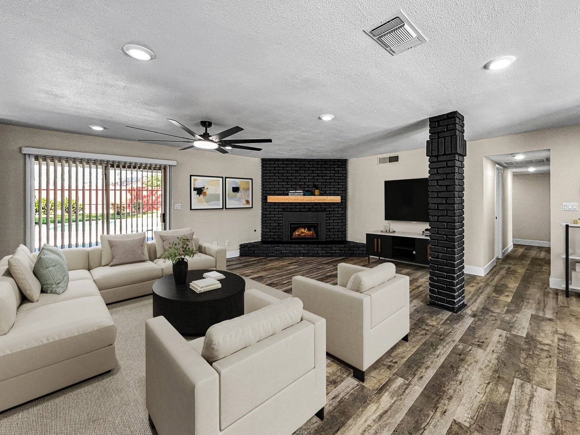 Living room with beige couches, a black round coffee table, a black brick fireplace with wood mantel, a wall-mounted TV, a ceiling fan, large window with vertical blinds, and wood flooring.