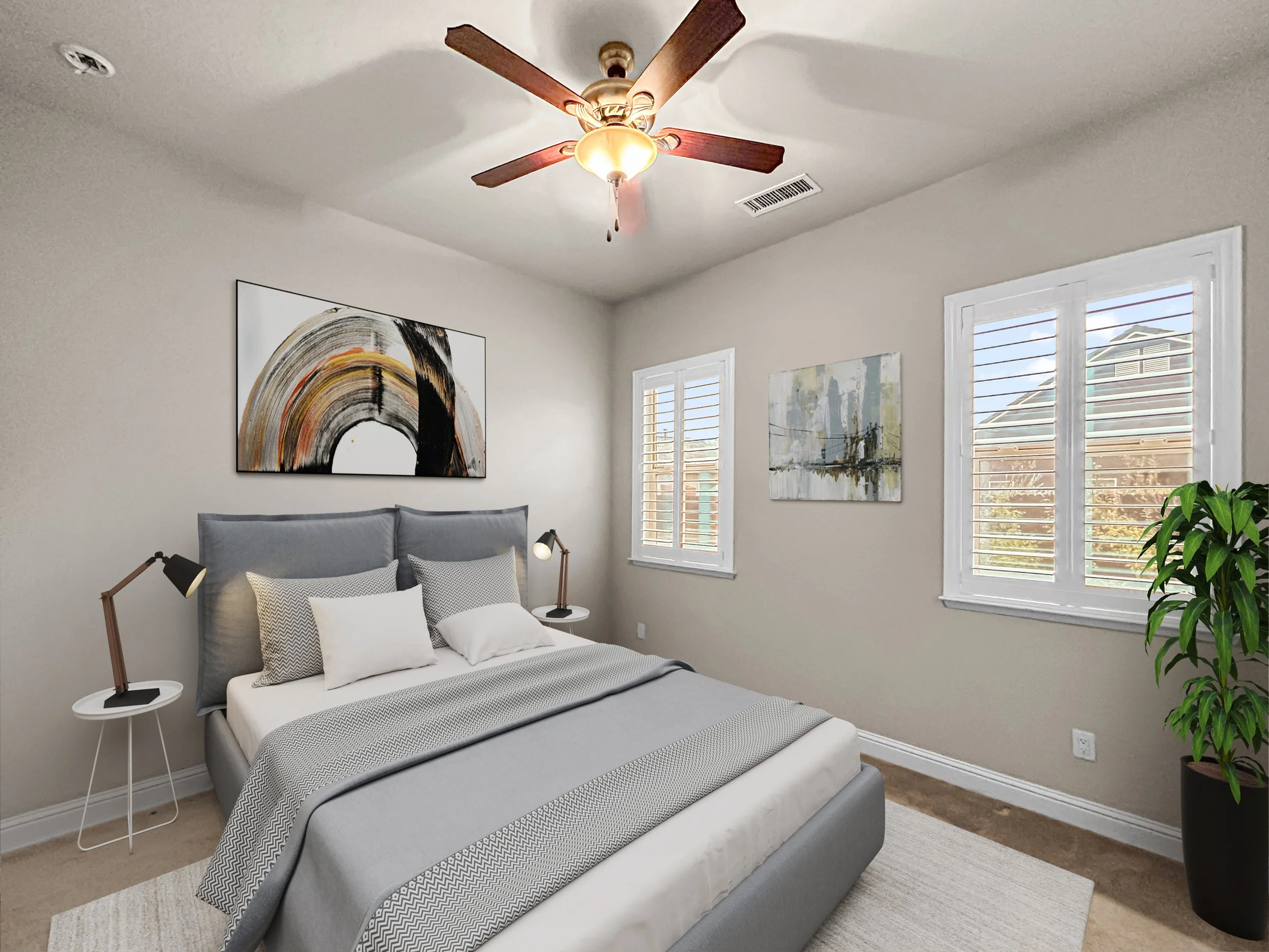 A bedroom with a bed, two side tables with lamps, framed artwork on the walls, windows with blinds, a ceiling fan, and a potted plant.
