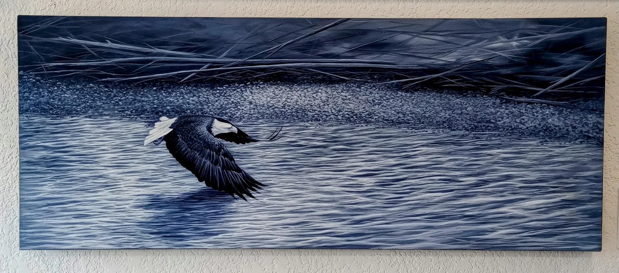 Monochrome blue acrylic painting of a bald eagle flying low over rippling water by Tammy Zinke