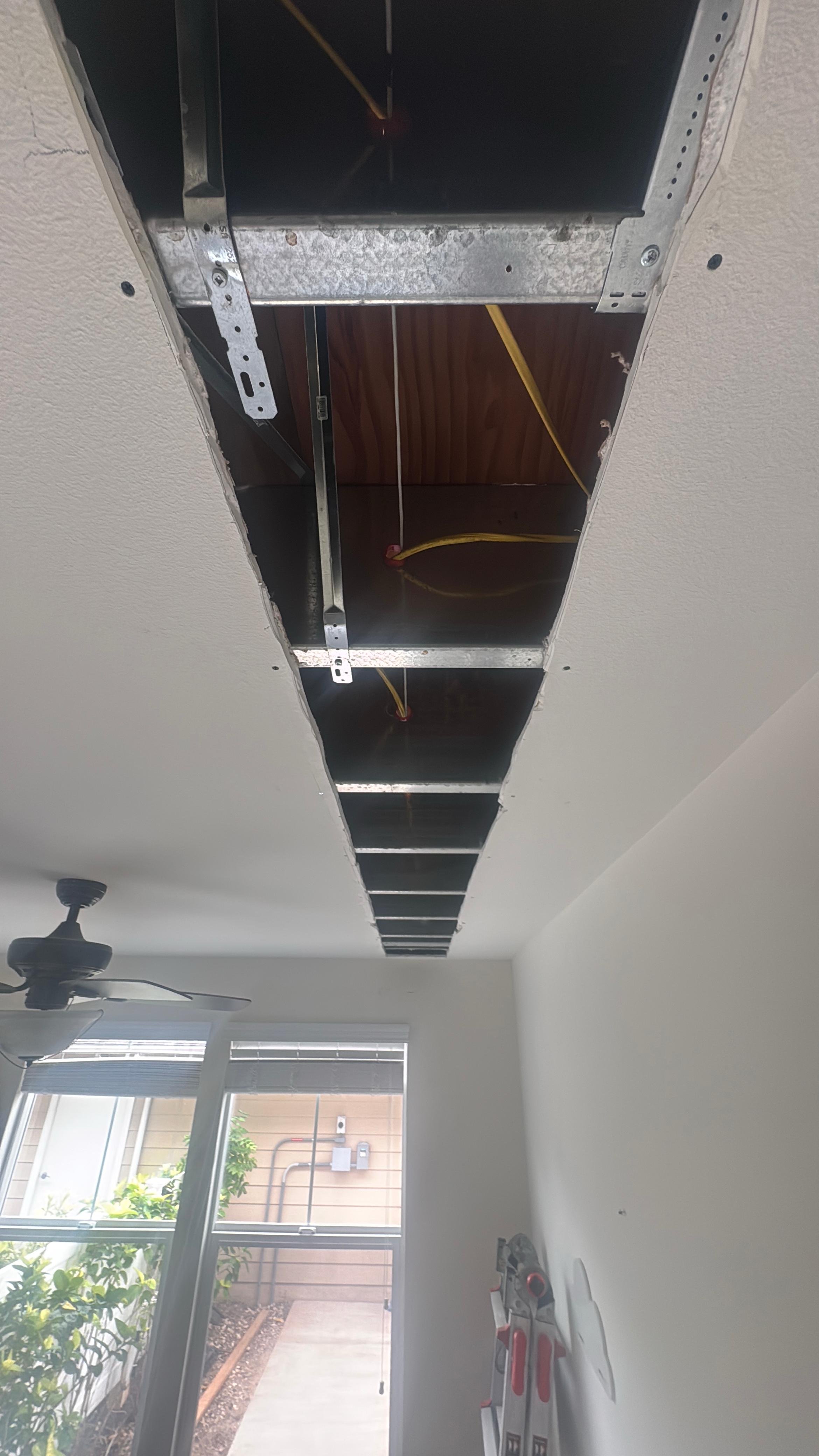 Before ceiling drywall repair showing a long open cut with exposed framing and electrical wiring that required proper patching and ceiling restoration.