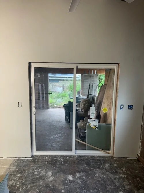 Interior of a house under renovation with a sliding glass door leading to a backyard.