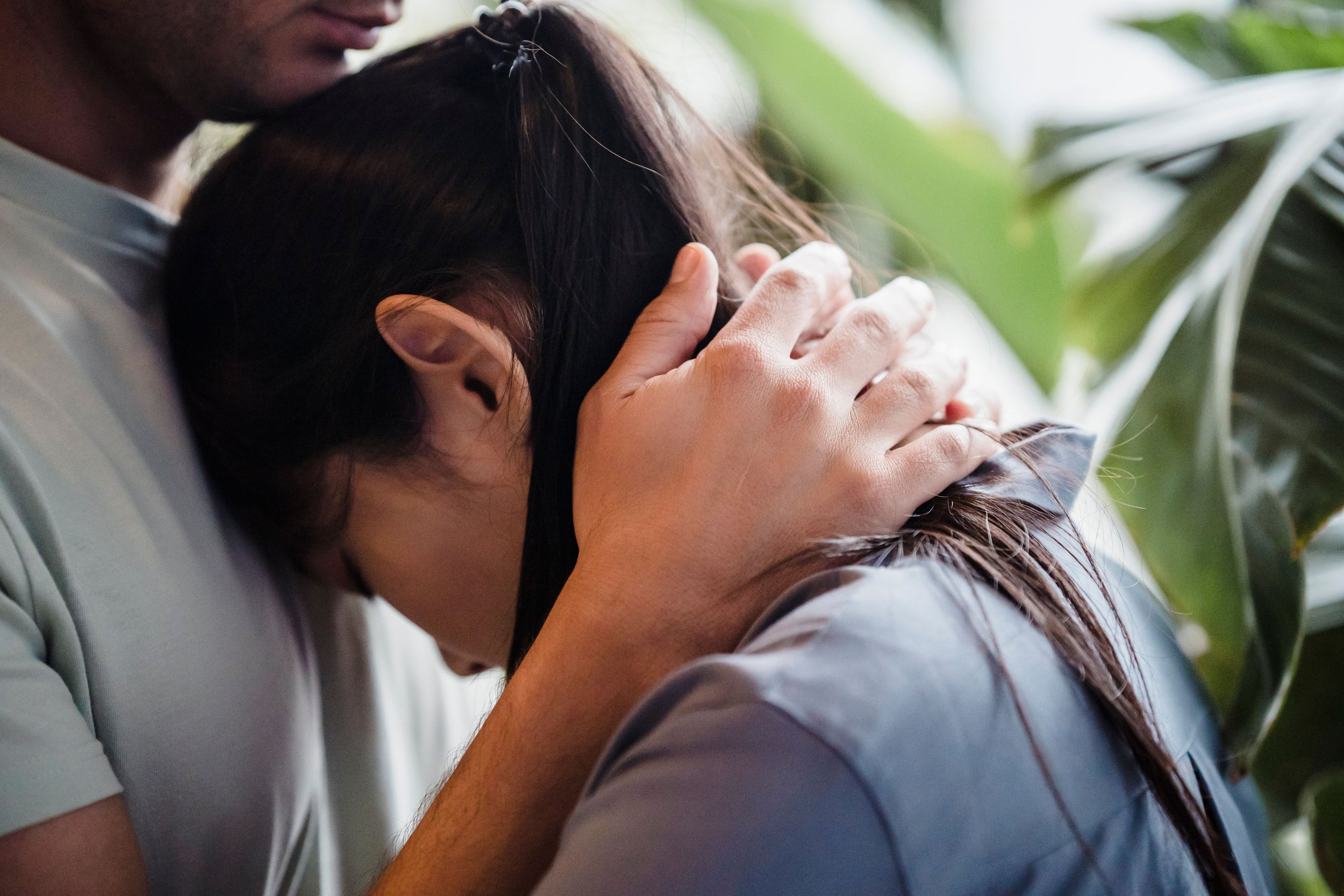 A person leaning their head into their partner's hands for comfort, seeking reassurance.