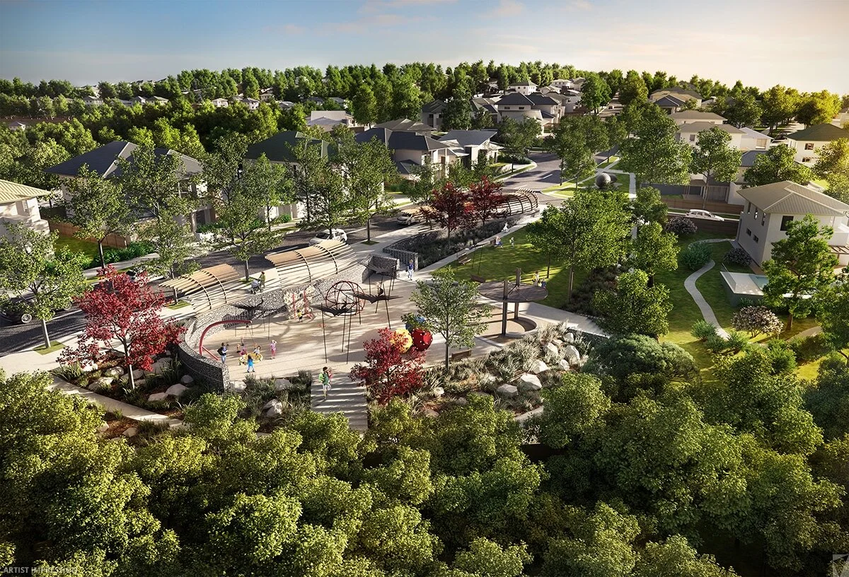 A park with playground equipment, surrounded by green trees, with residential houses and a street in the background.