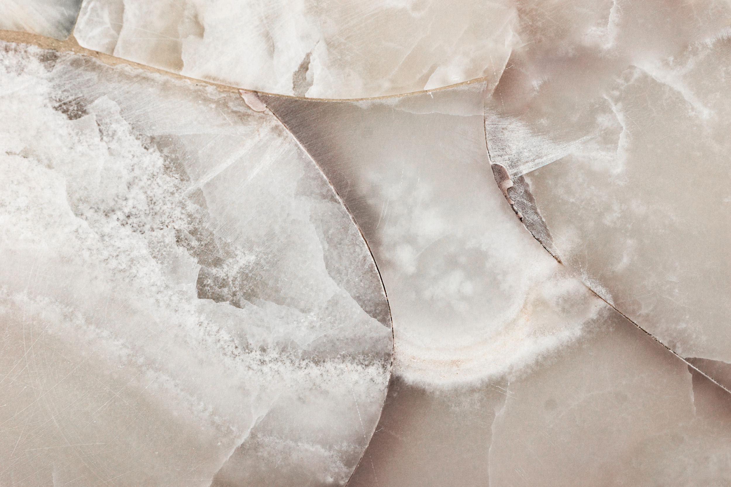 Close-up of broken and cracked marble or stone surface with various shades of beige, cream, and pink.