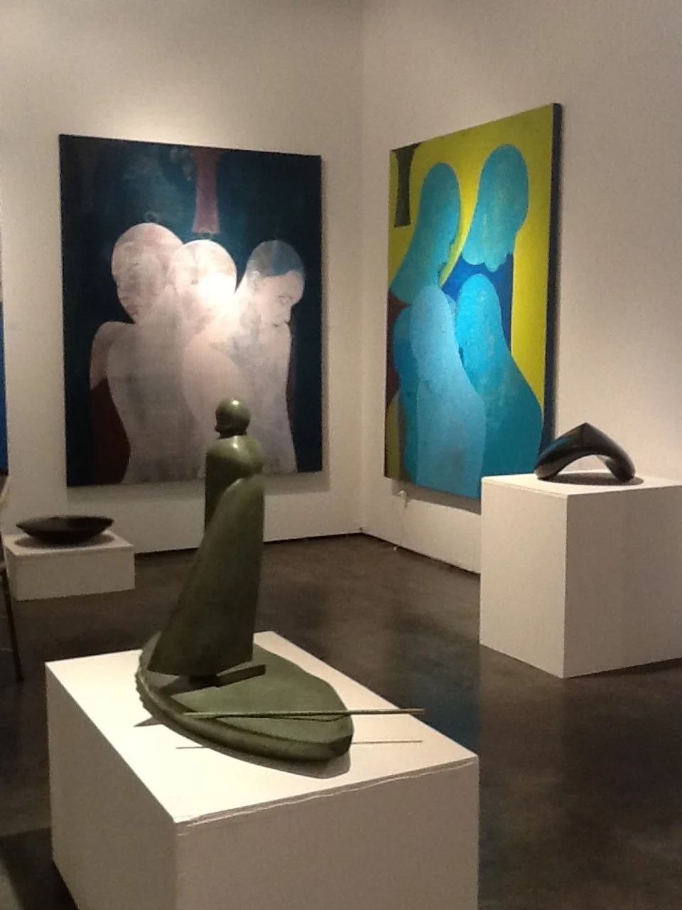 Artwork and sculptures displayed in an art gallery, featuring abstract paintings and modern sculptures.
