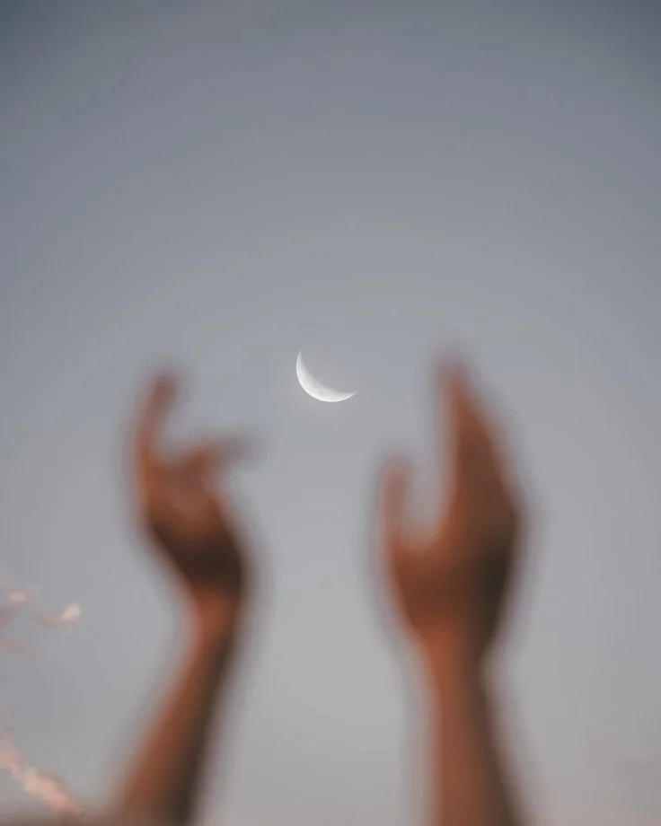 Blurred hands reaching towards the sky with a crescent moon visible in the background.