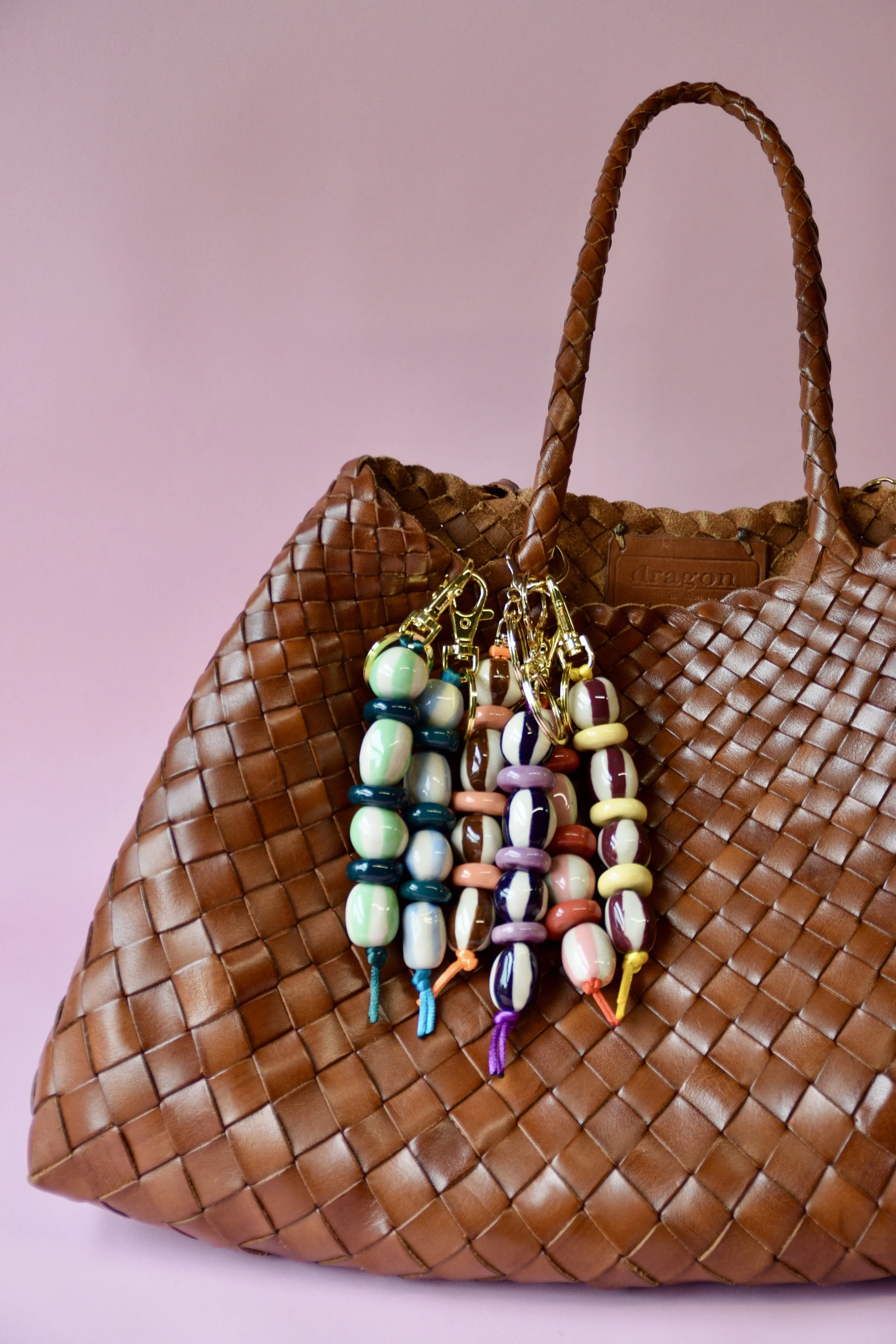 Colourful ceramic bag charms styled on a brown woven bag