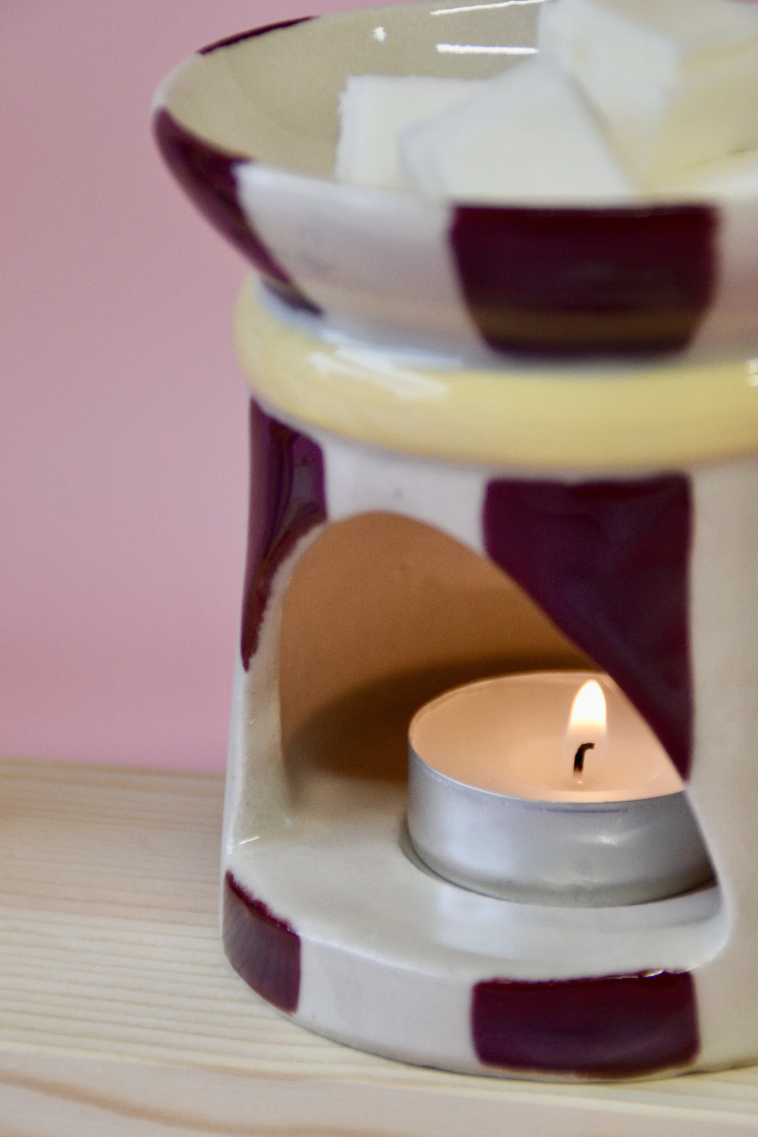 Burgundy and yellow ceramic wax burner with lit tea light