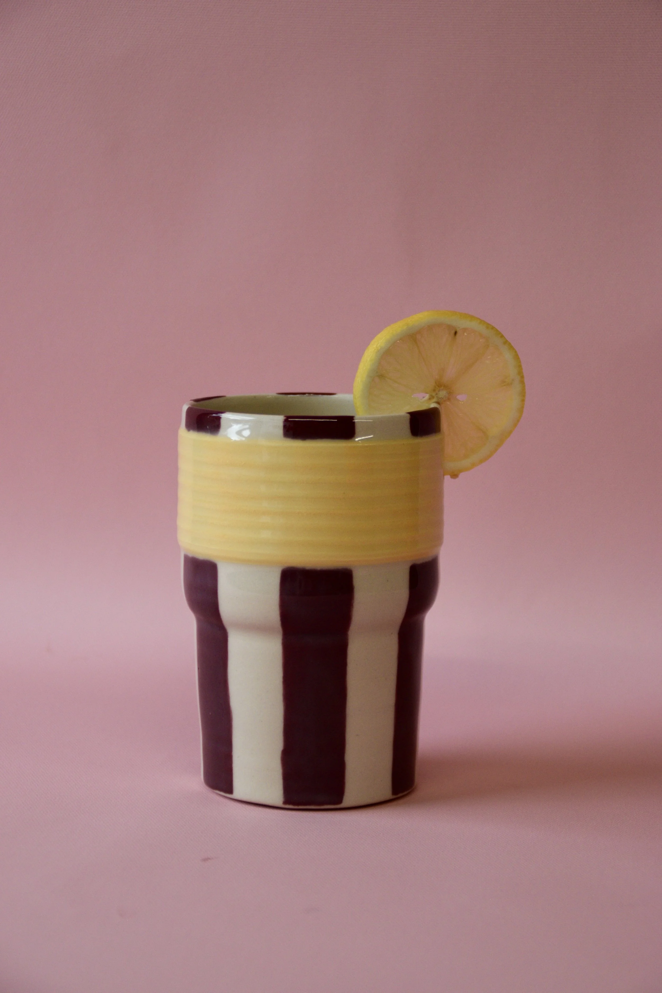 Burgundy and yellow striped ceramic tumbler with lime