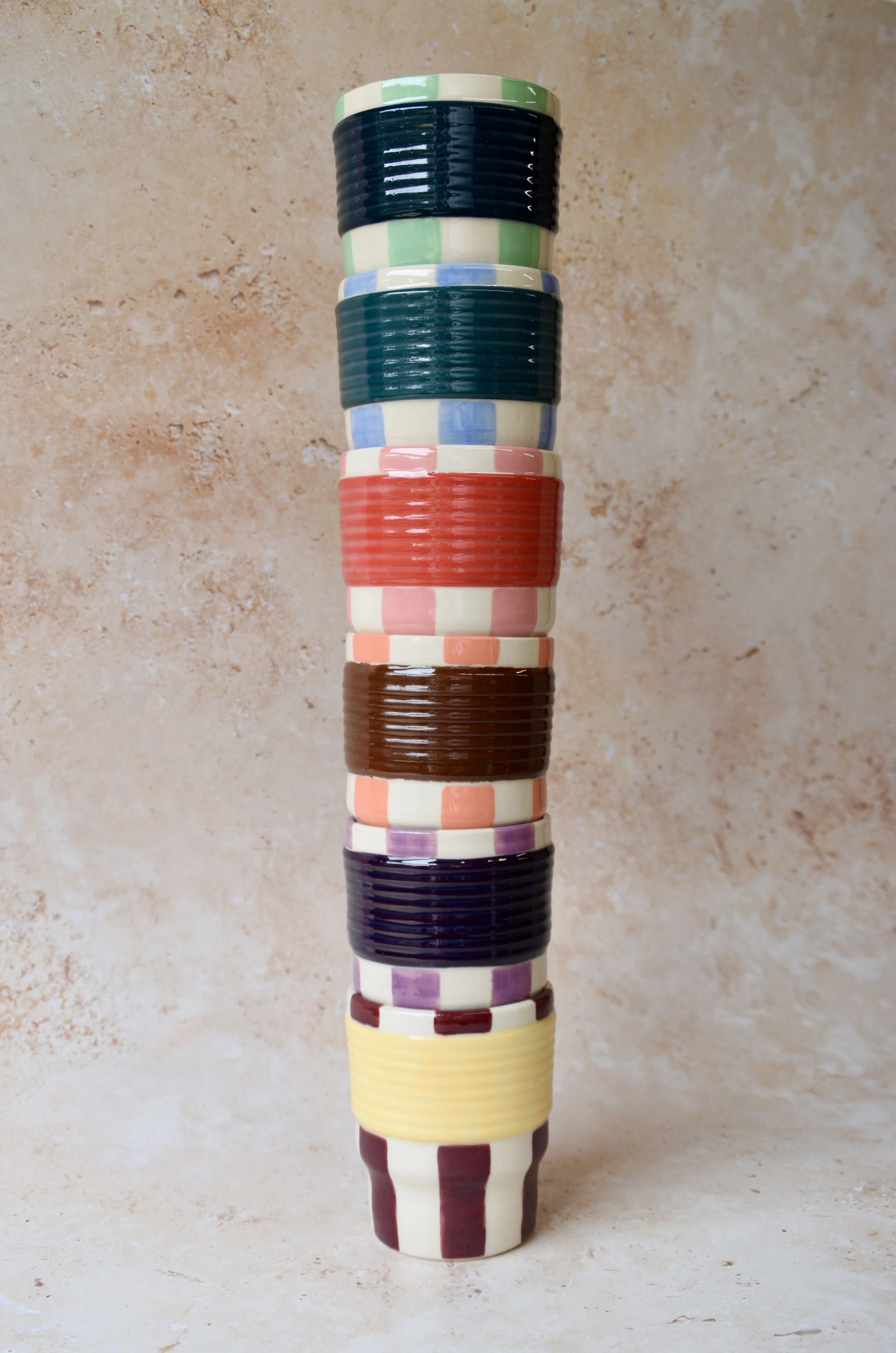 Stack of colourful striped ceramic tumblers