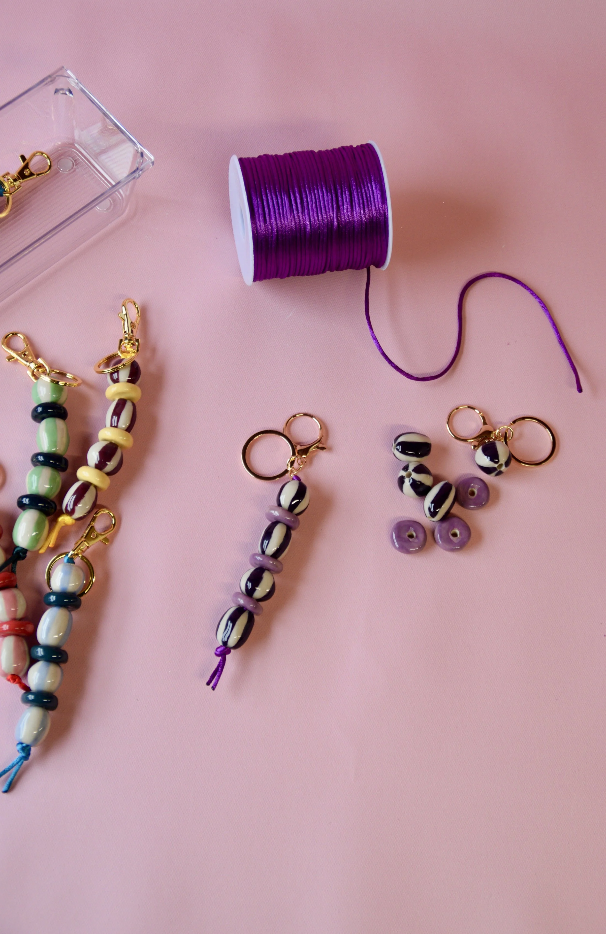 Handmade ceramic bag charms and beads on a pink background