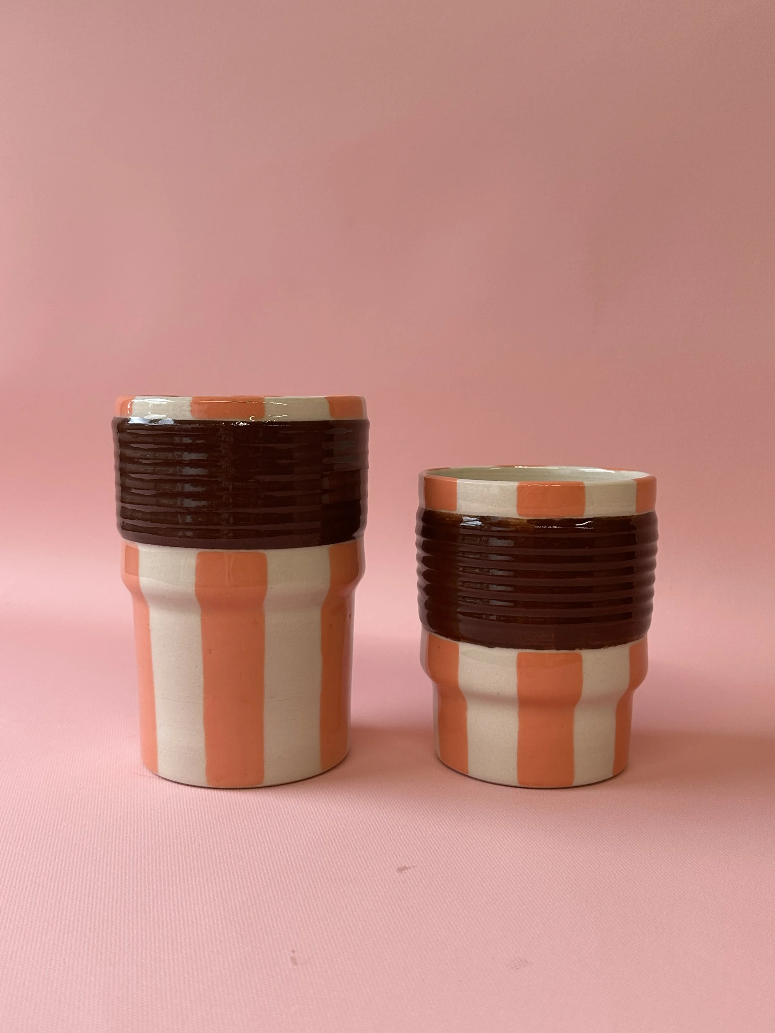 Large and small orange and brown striped ceramic tumblers
