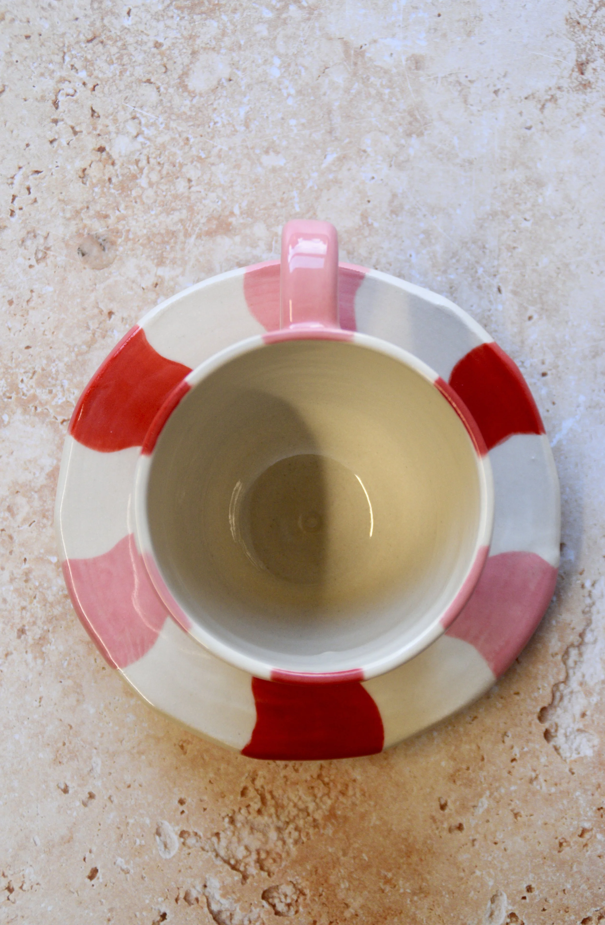 Top view of handmade wavy striped ceramic cup and matching saucer showing hand-painted pattern.