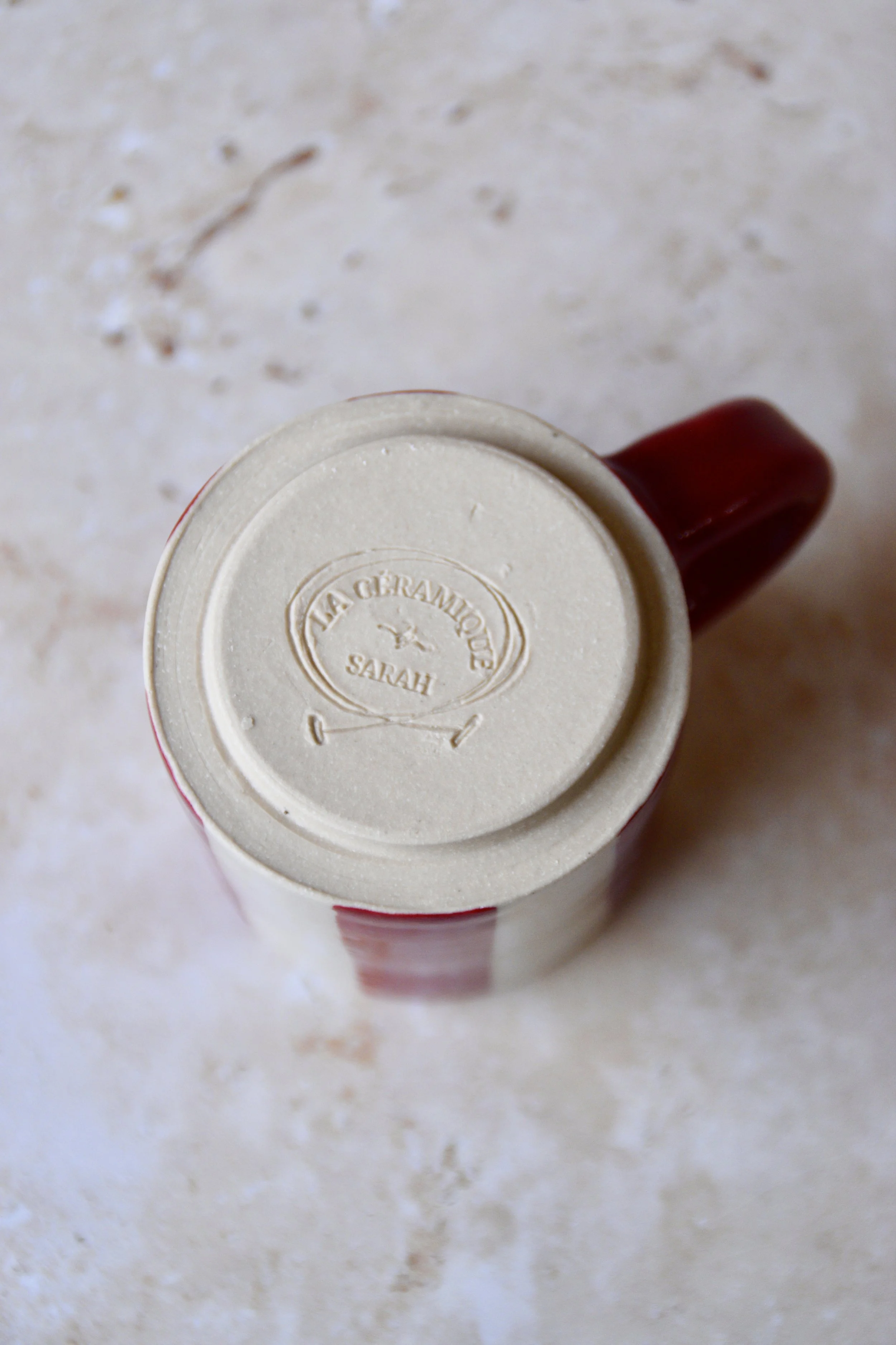 Bottom view of handmade ceramic espresso cup showing maker’s stamp “La Céramique by Sarah” impressed into the clay.