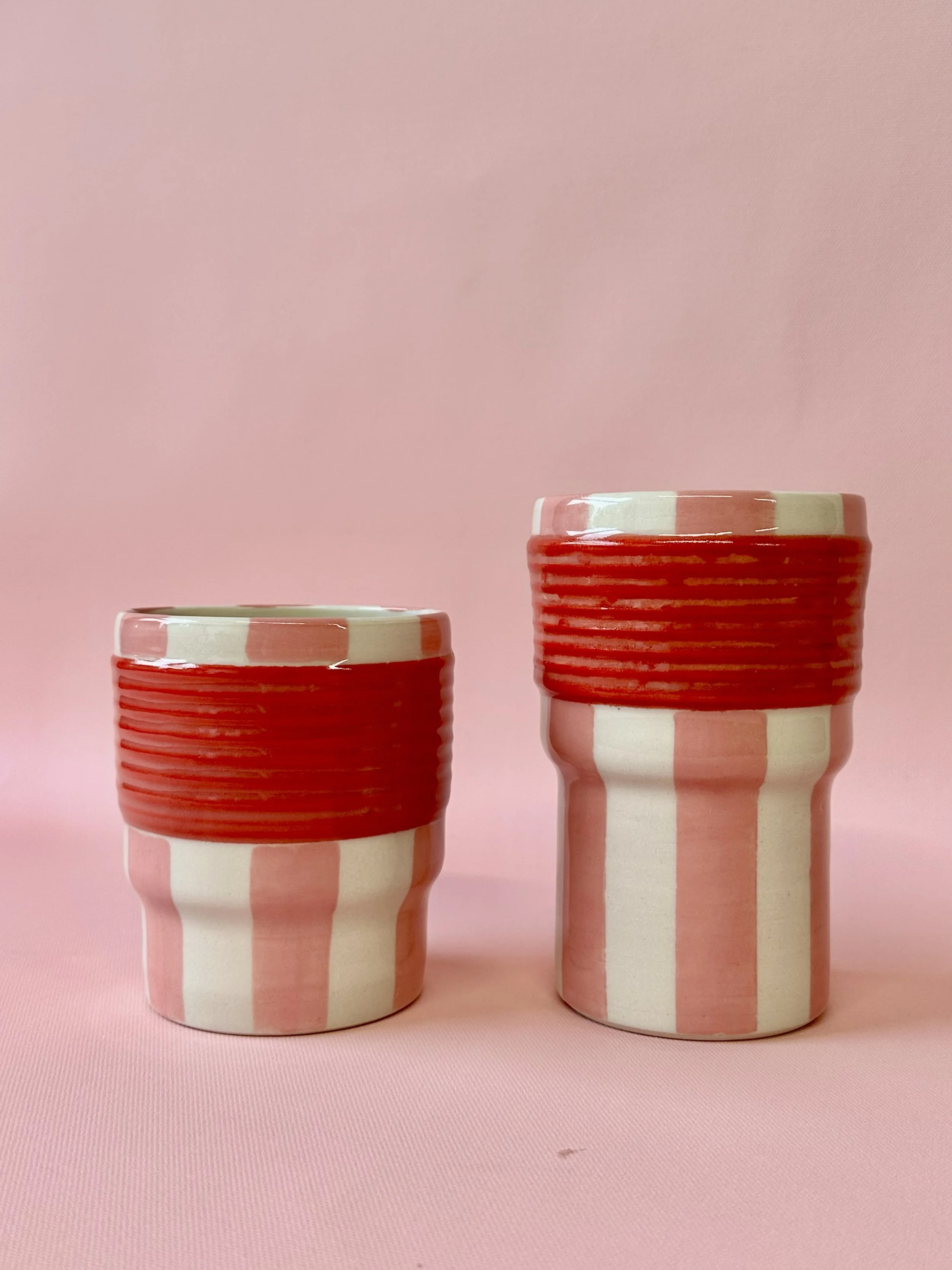Large and small pink and red striped ceramic tumblers