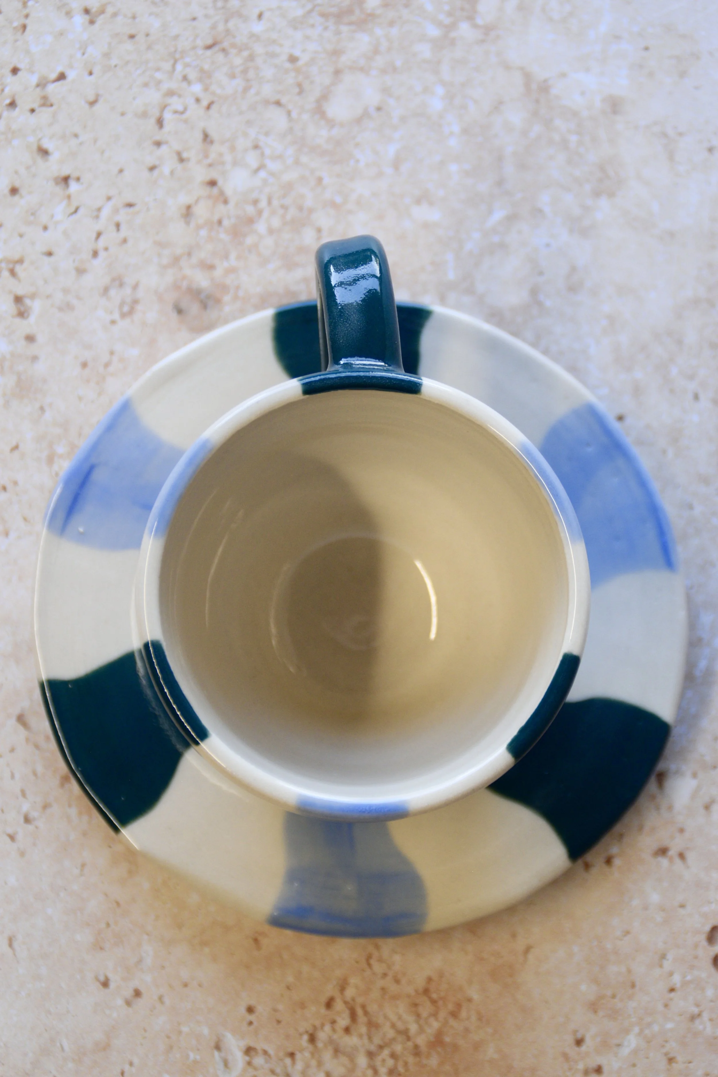 Top view of handmade wavy striped ceramic cup and matching saucer showing hand-painted pattern.
