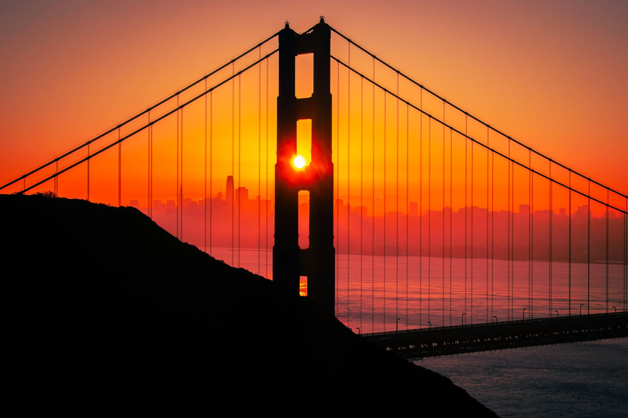 Sunset view of the Golden Gate Bridge in San Francisco with the city skyline in the background.
